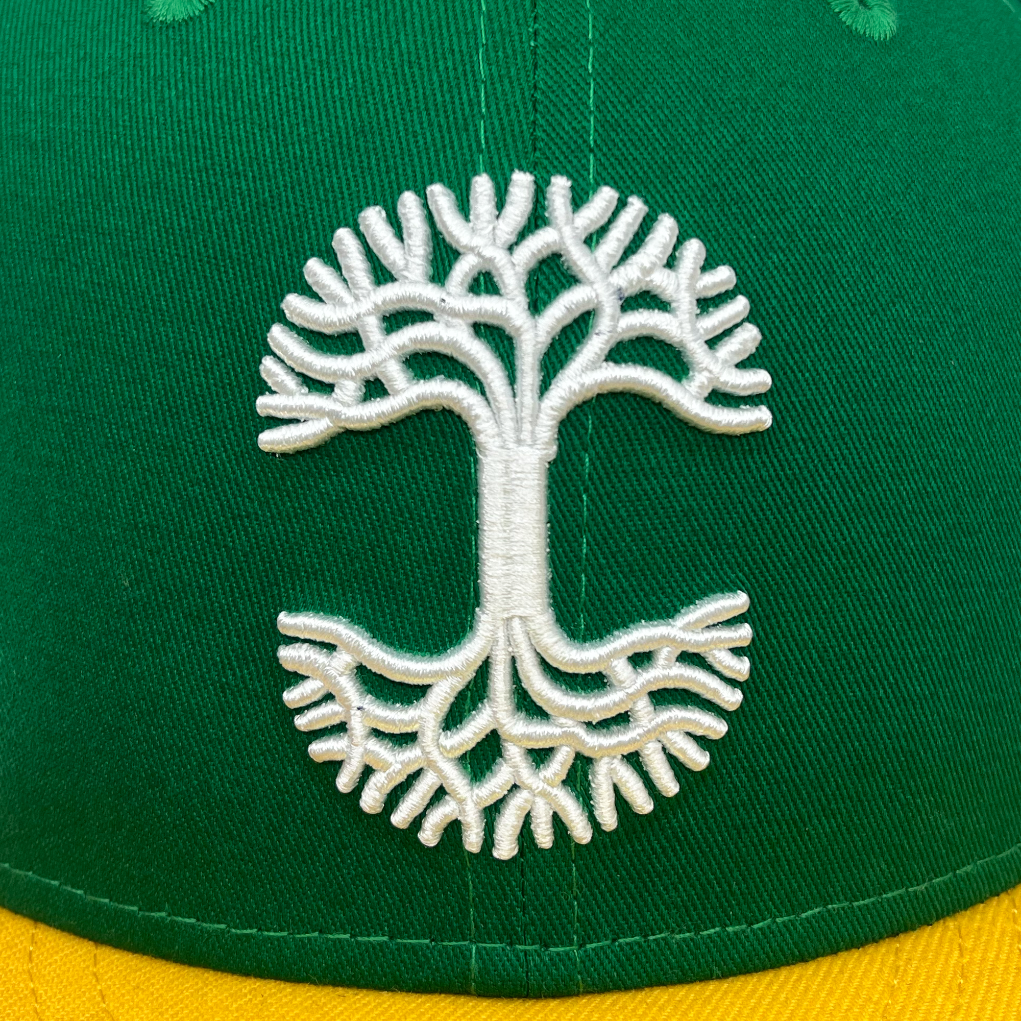 Detail close-up of white embroidery of Oaklandish tree logo.