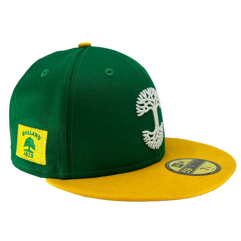 Side view of green fitted New Era cap with yellow visor & Oakland 1852 side patch.