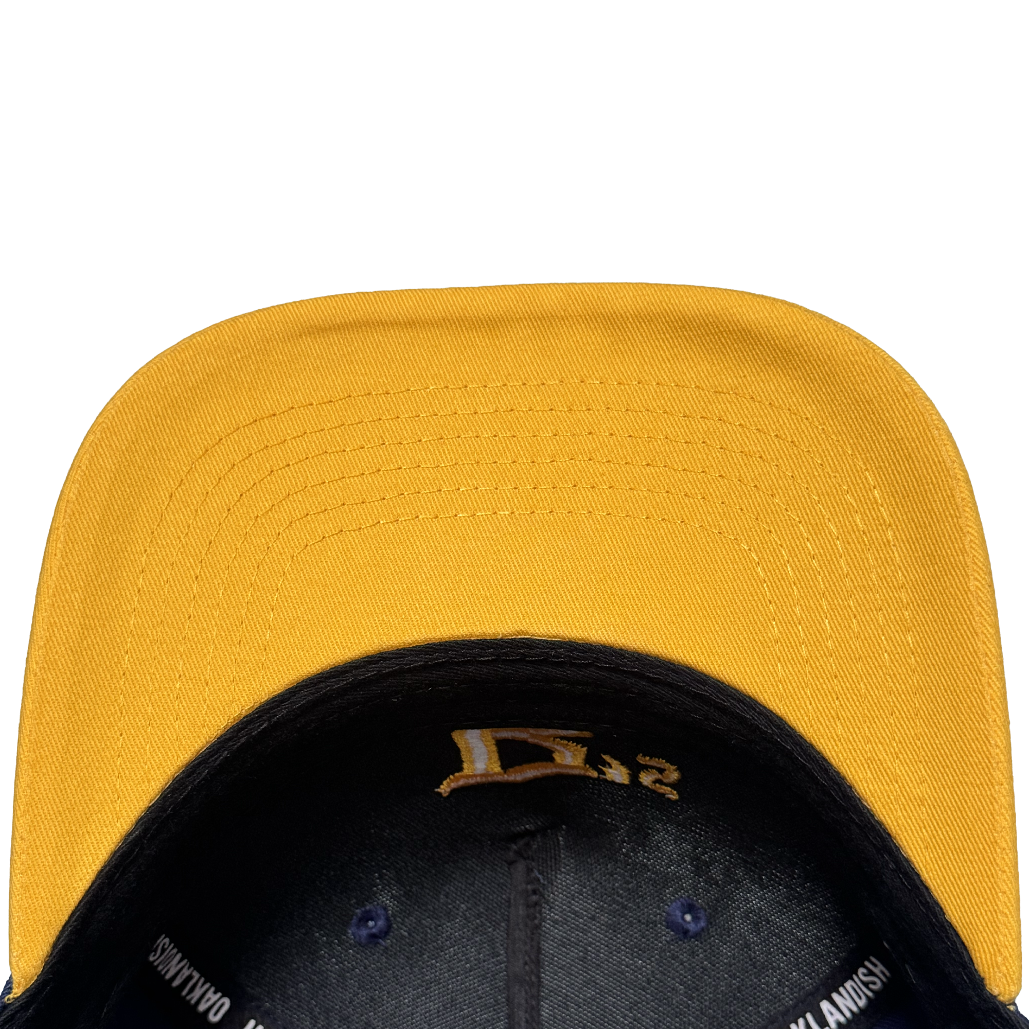A close-up, top-down view of the Oakland Ballers 5 Panel Cap by Oakland Ballers shows its yellow color, black underside, brim stitching, black embroidered interior details, and partial white text on the inner band against a white background.