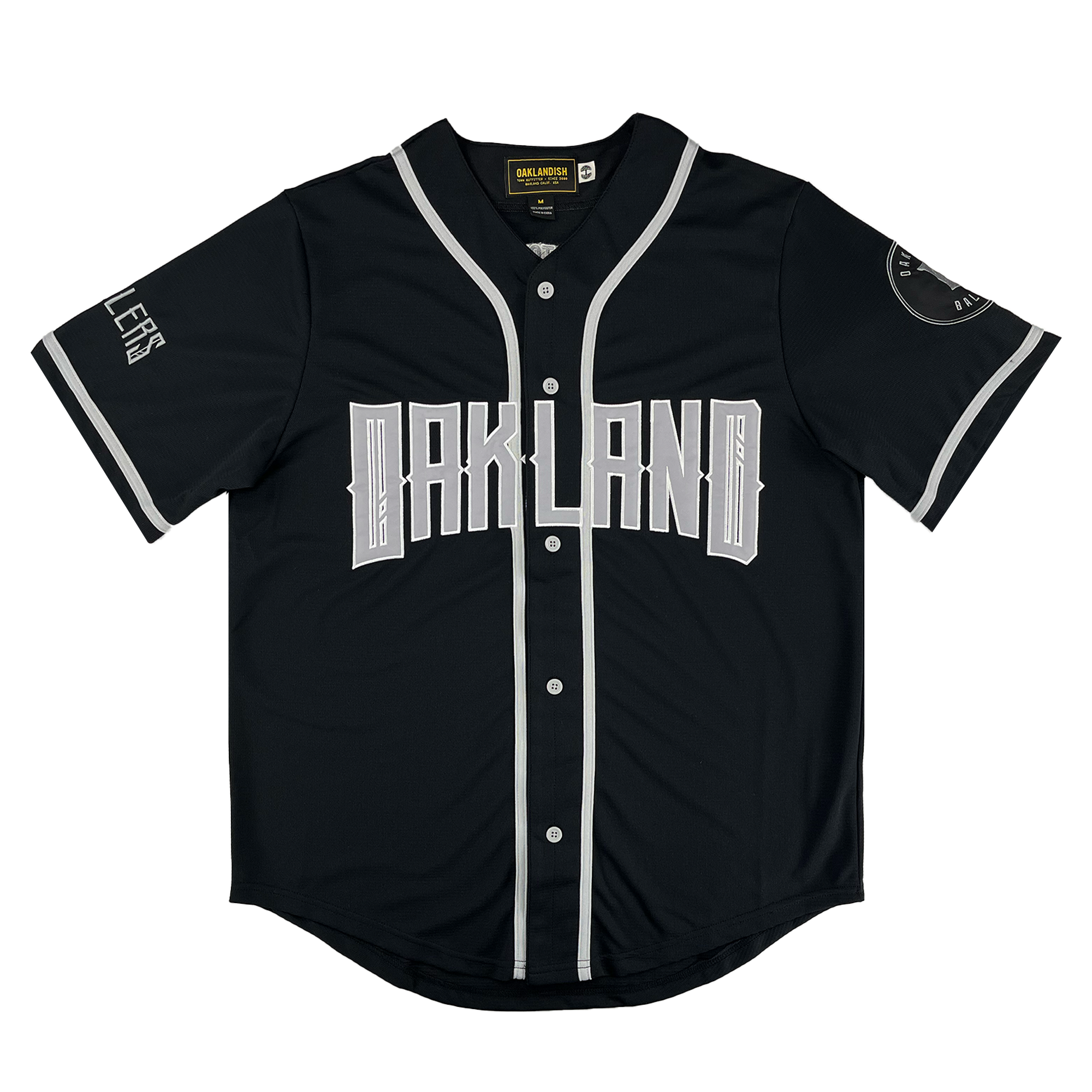 The Oakland Ballers Button Up Jersey by Oakland Ballers features a black design with white buttons, sleeve, and collar trim. "OAKLAND" is boldly printed across the chest, representing the Pioneer League baseball team. White details accent sleeves and cuffs.