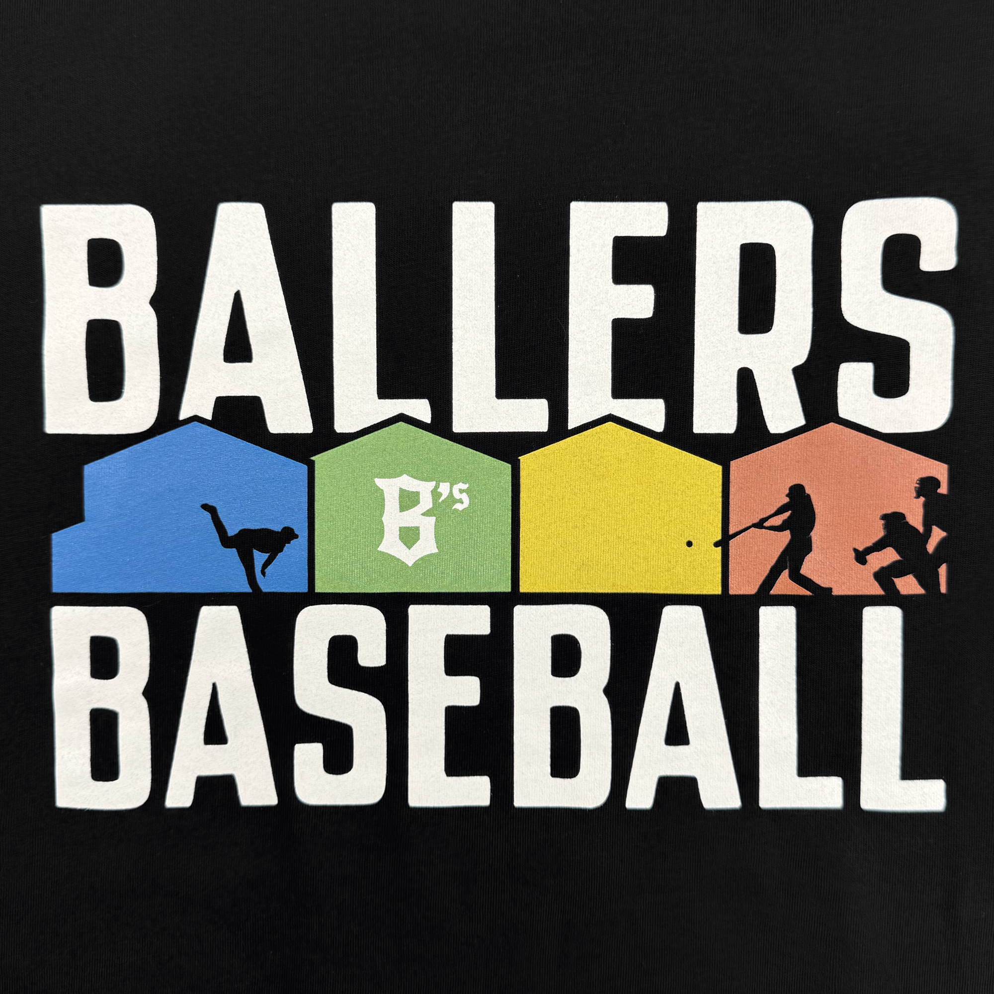 The Warehouse Tee by Oakland Ballers features the words “BALLERS BASEBALL” in bold white, with four colored house silhouettes—blue, green, yellow, orange—each displaying a black baseball action figure.