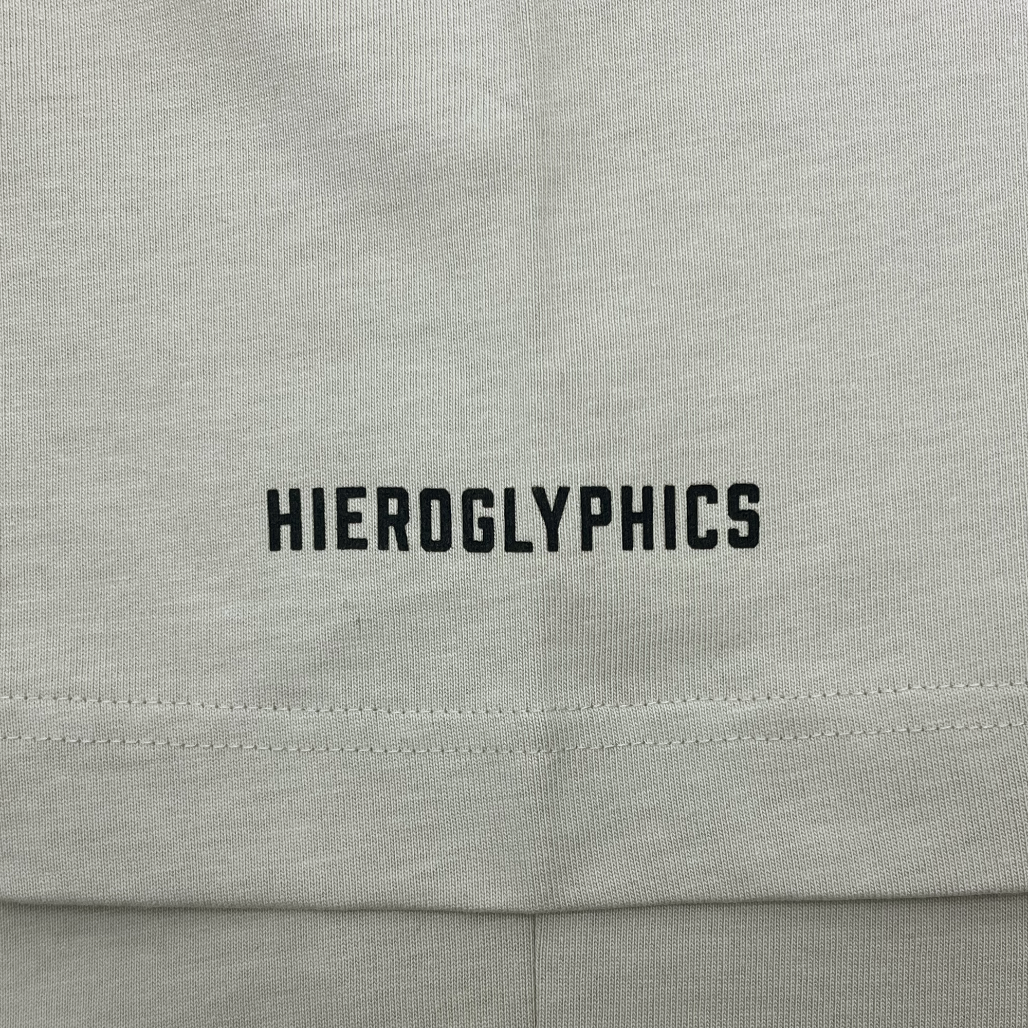 Detailed close-up of black HIEROGLYPHICS wordmark on the sleeve of a bone-colored baseball jersey.