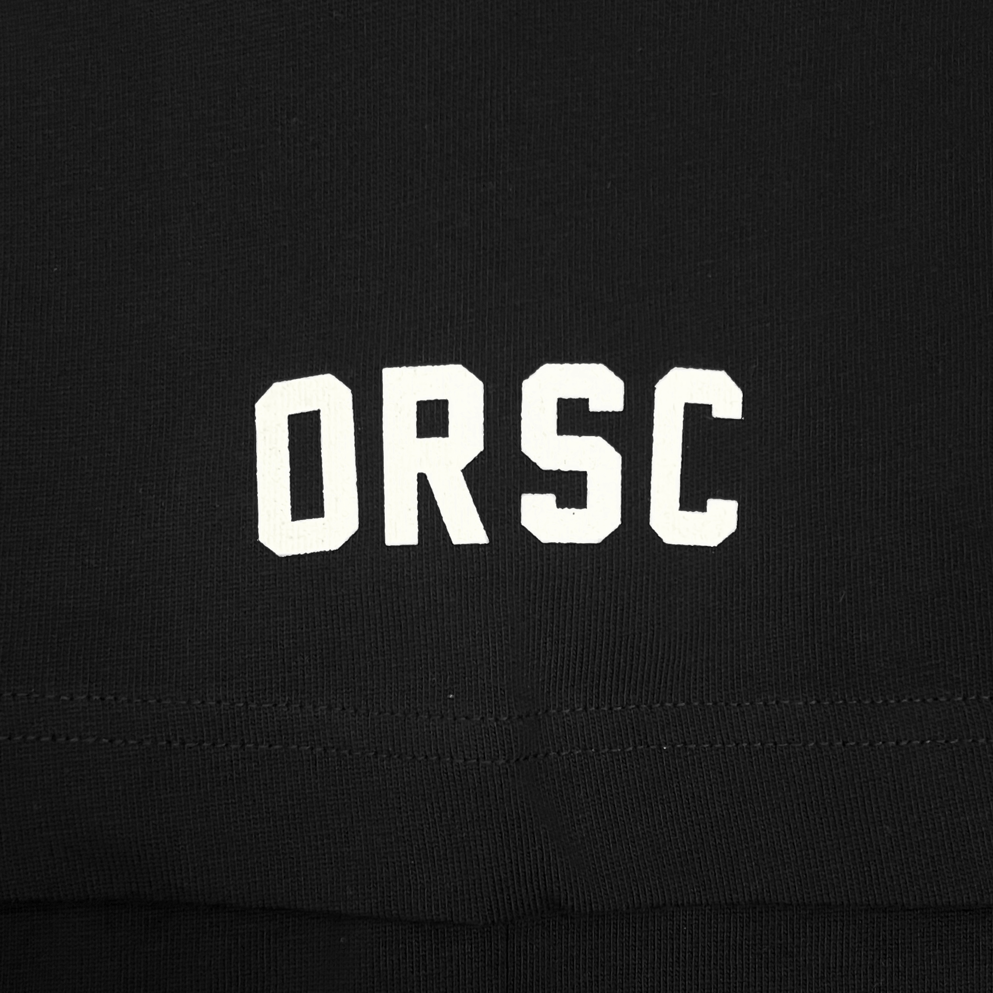 Detailed close-up of white ORSC wordmark on the sleeve of a black baseball jersey.