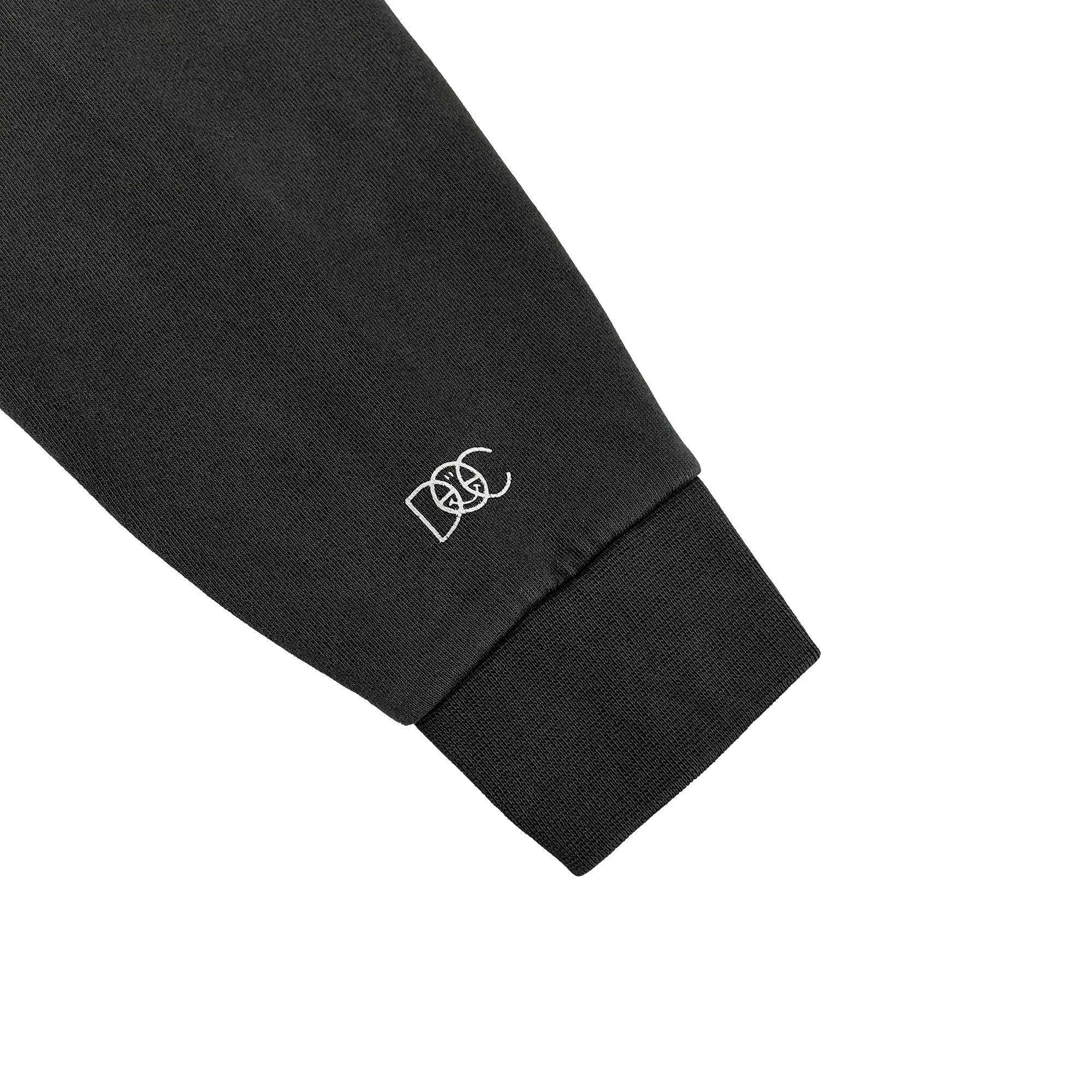 Close-up of white DOC logo wordmark on a pigment black pullover hoodie sweatshirt sleeve.