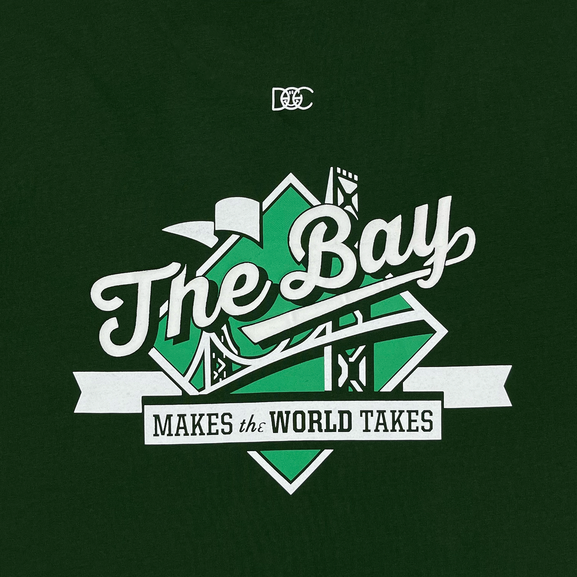 Detailed close-up of The Bay Makes The World Takes green and white logo graphic on a forest green t-shirt.