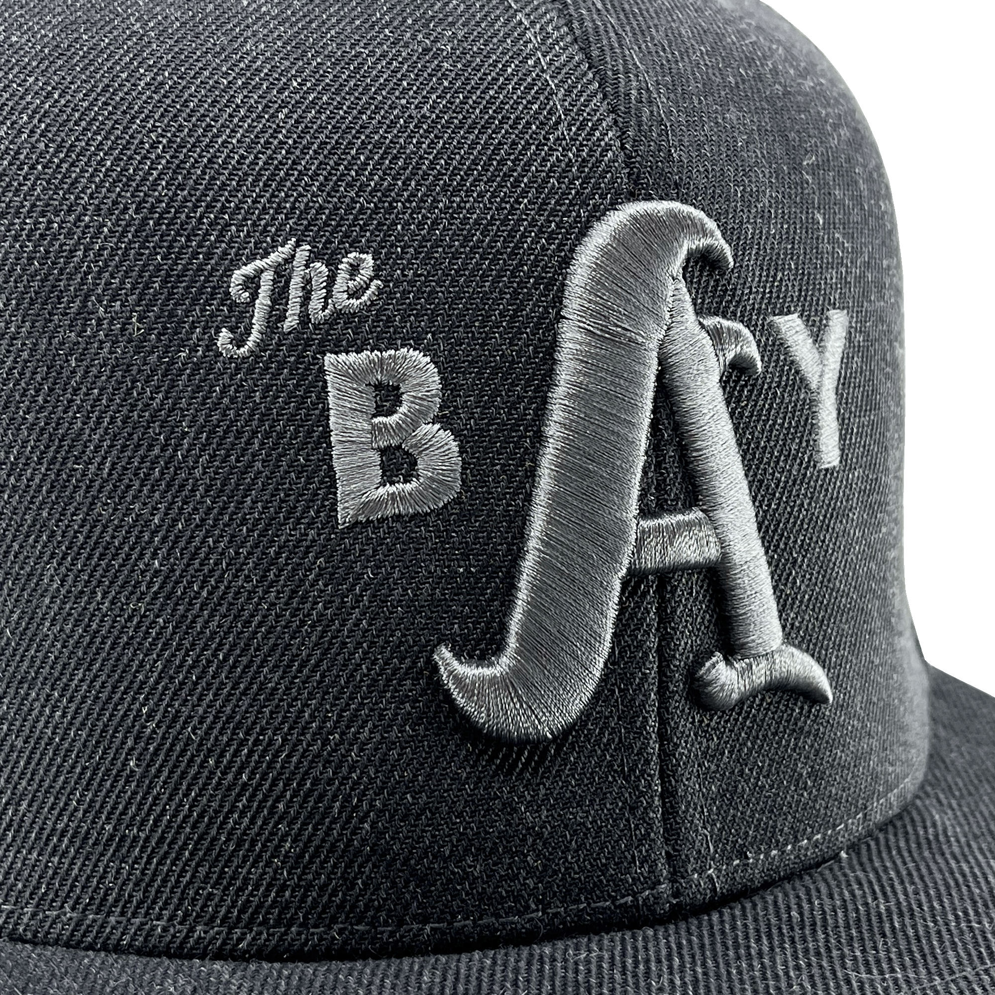 Close-up of a 3D white embroidered The Bay logo on the crown of a charcoal hat.
