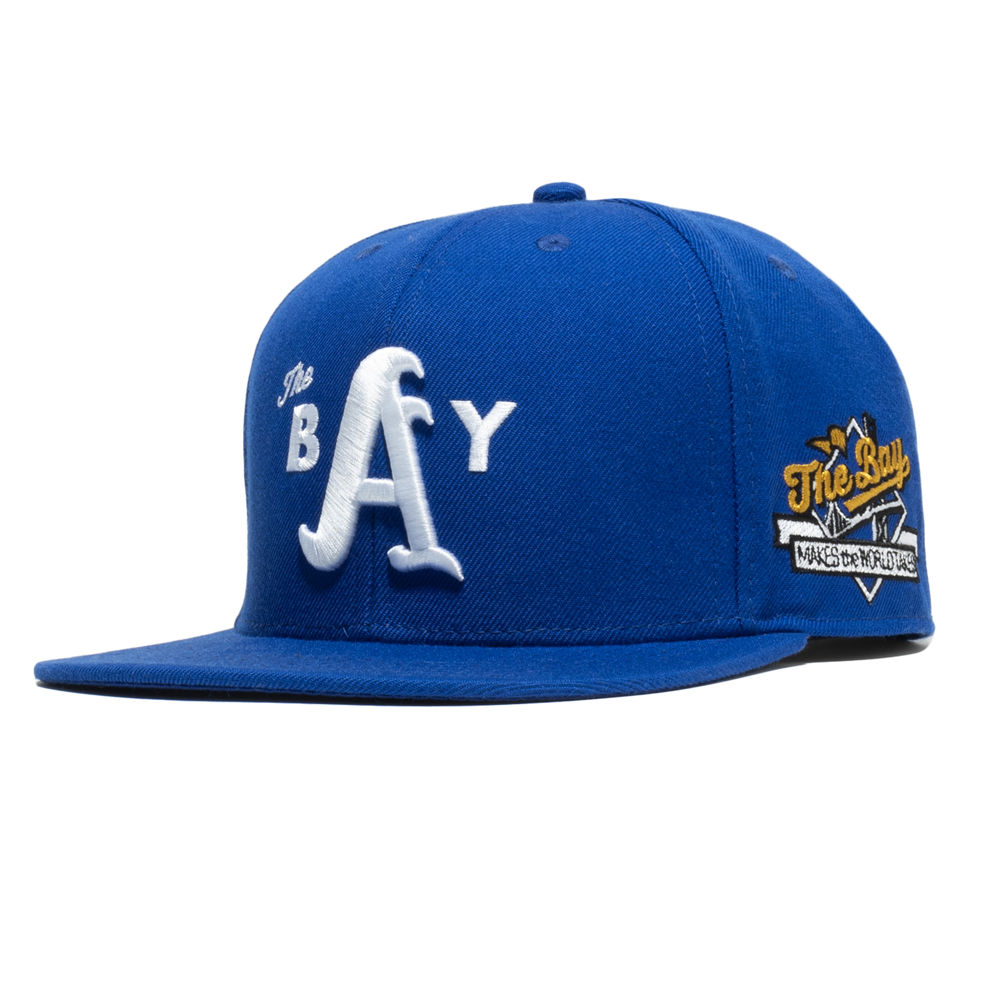 The Bay Snapback by DOC from Oaklandish is a royal blue hat adorned with "The Bay" embroidered in large white letters on the front. It also features a patch on the right side displaying a stylized image of a bridge and basketball hoop, along with the text "The Bay" and "Made by the Future.