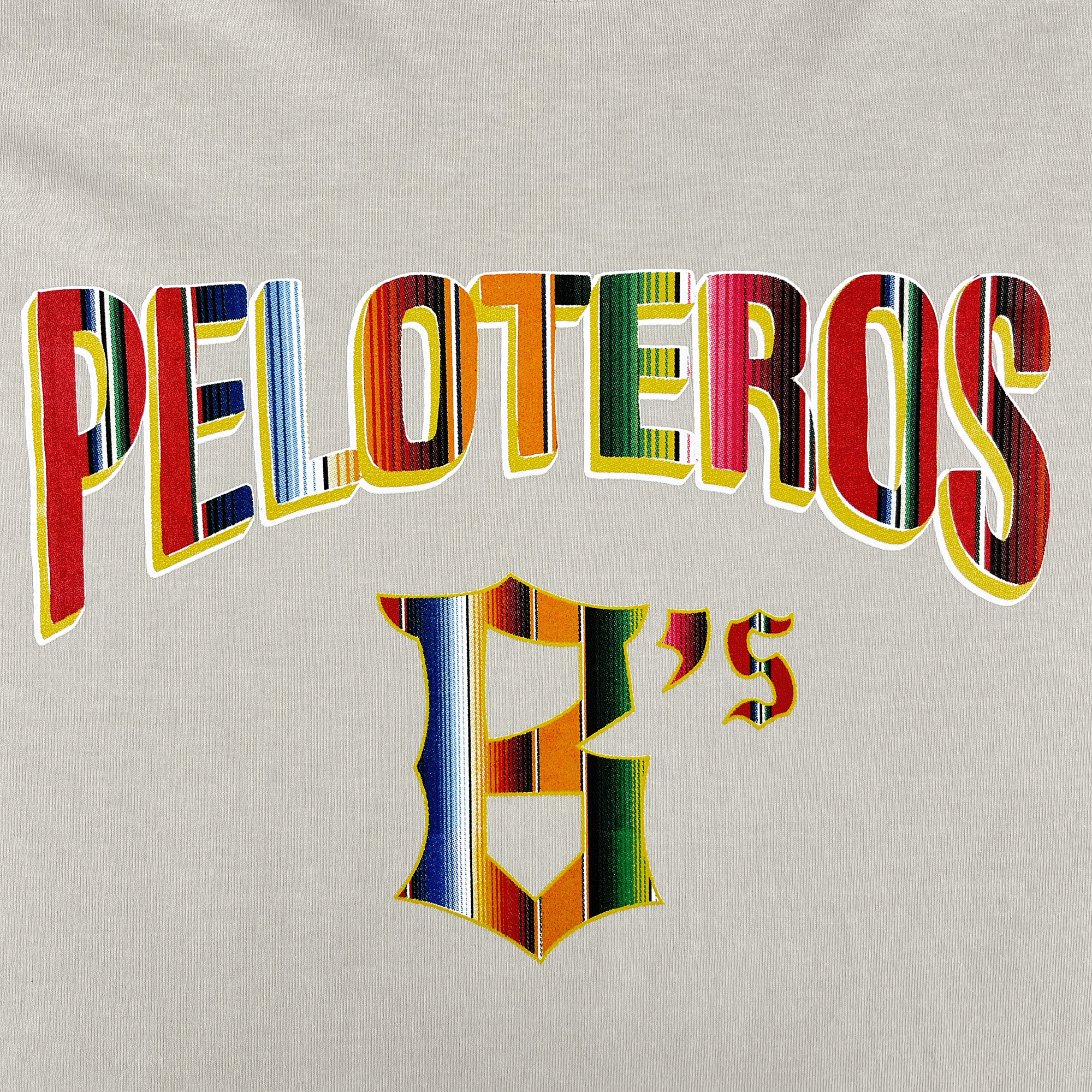 The Oakland Ballers’ Oakland Beisbol Heavy Tee features bold, uppercase “PELOTEROS” and a “B’s,” with vibrant, stripe-patterned text inspired by traditional Mexican textiles on a light beige background.