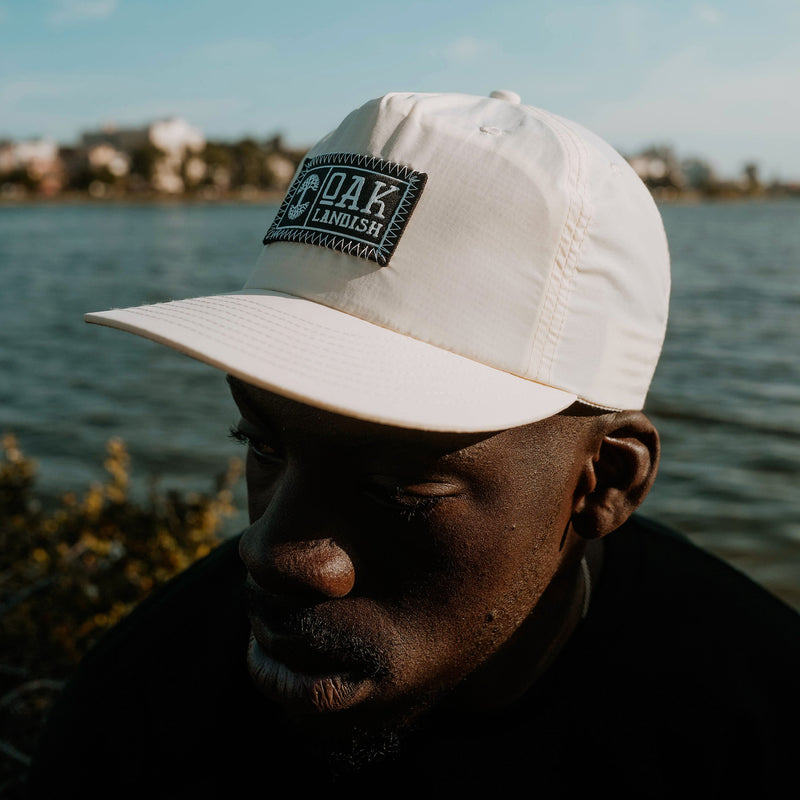 Male model wearing Bommie surf nylon snapback cap with embroidered woven label patch at center of crown.