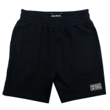 Front view of black fleece shorts with embroidered Oaklandish woven label near wearer's left leg hem.