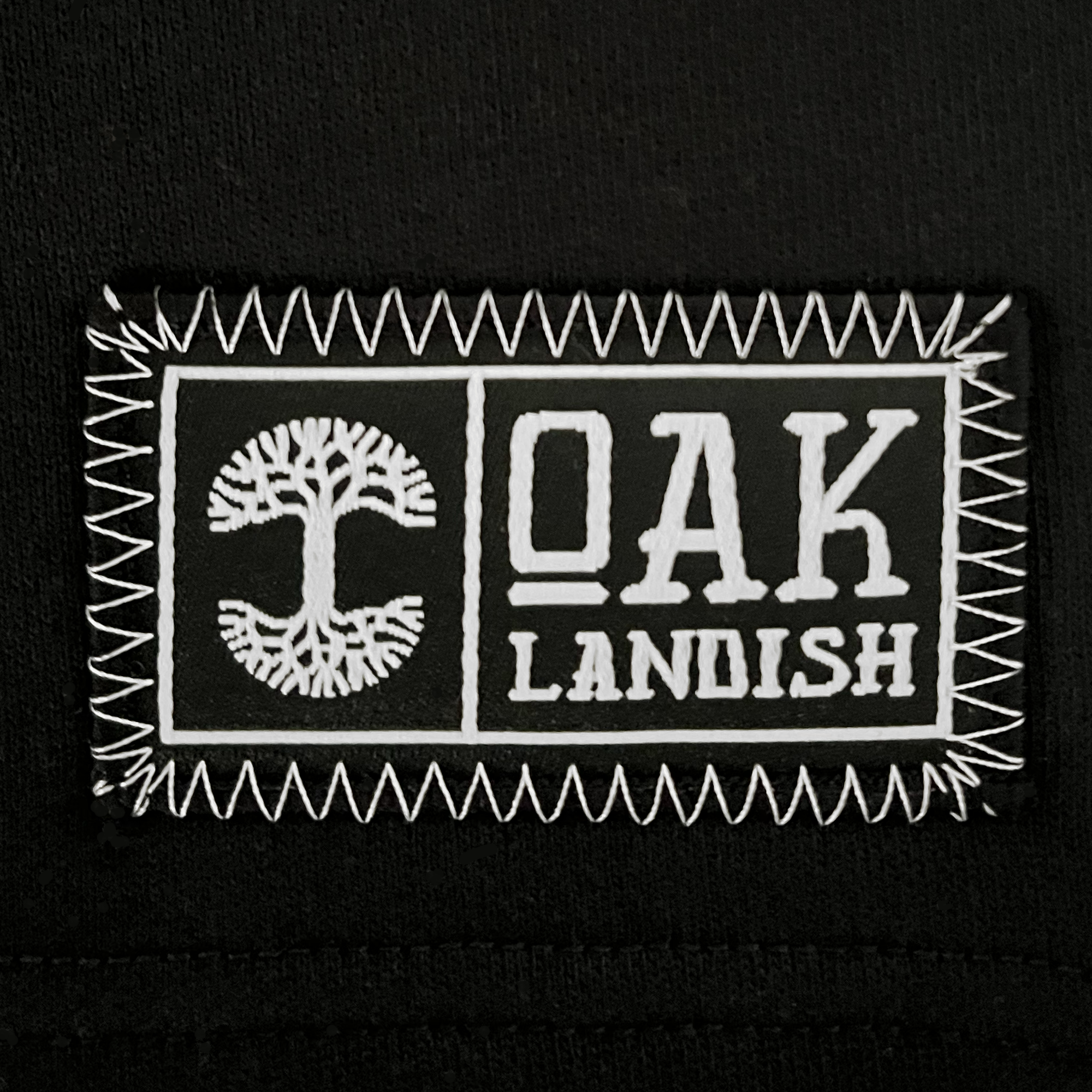Detail close up of embroidered Oaklandish woven label on black sweat shorts.