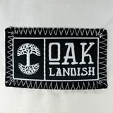 Detailed close up of embroidered Oaklandish black and white woven patch at center of ecru nylon snapback cap.