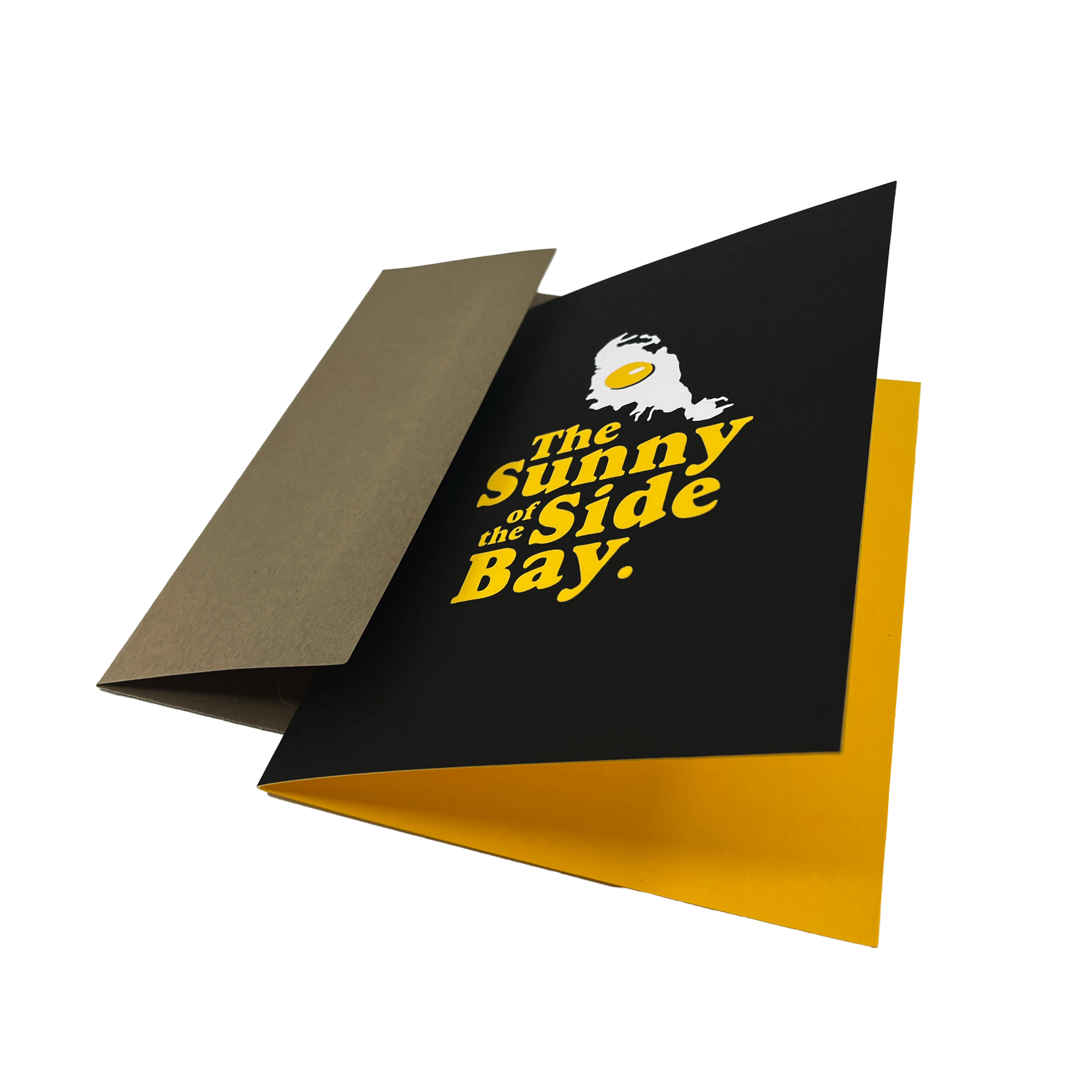 Black greeting card with The Sunnyside of the Bay wordmark and logo, open to expose the yellow inside, with a brown envelope