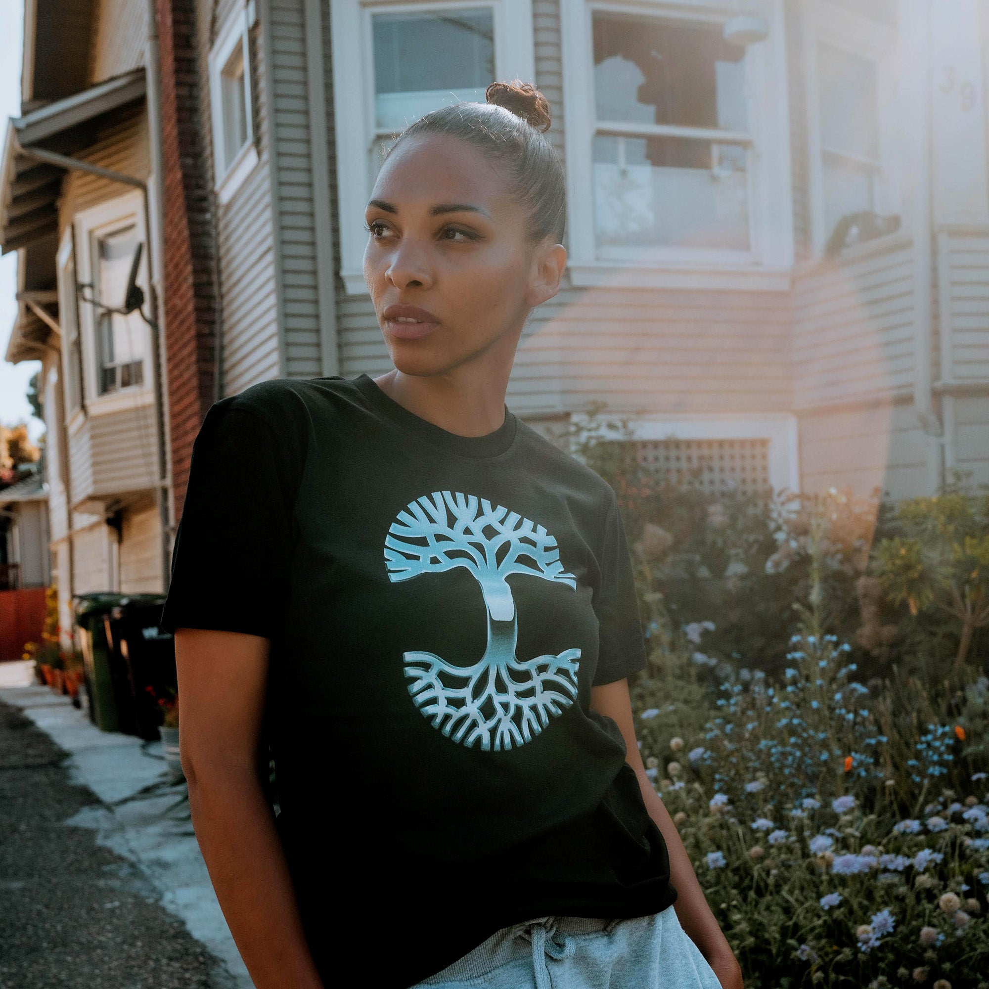 Female model outside wearing Oaklandish Chrome tree black t-shirt.