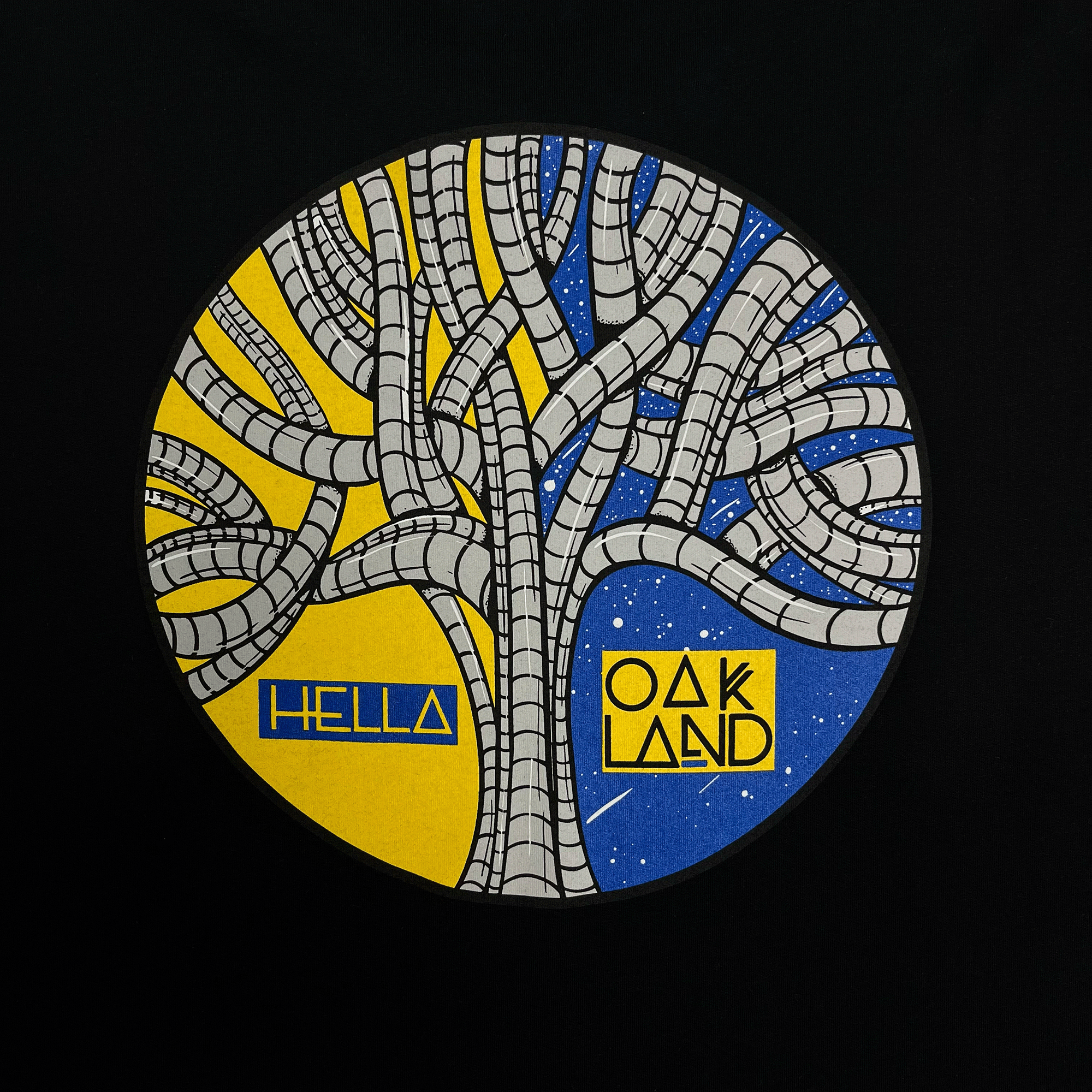 Close-up of blue, yellow, and grey HELLA OAKLAND circular tree graphic by artist HellaFutures on a black t-shirt.