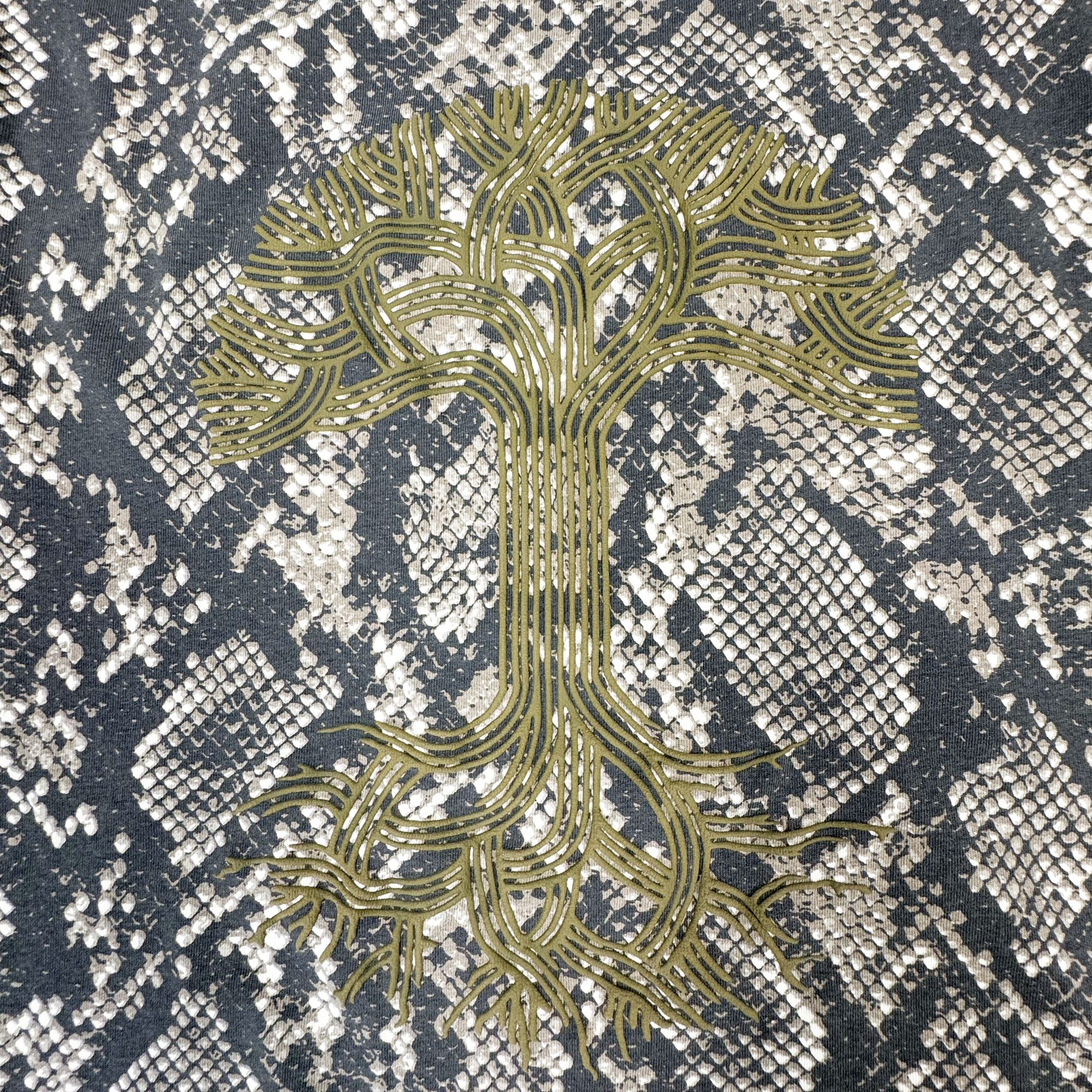 The Oaklandish Classic Logo LS Tee by Oaklandish features the brand’s iconic stylized golden tree logo, with intricate branches and roots set against a black and white snakeskin pattern background. This design artfully blends natural and geometric textures on a 100% cotton long sleeve t-shirt with vintage black sleeves.