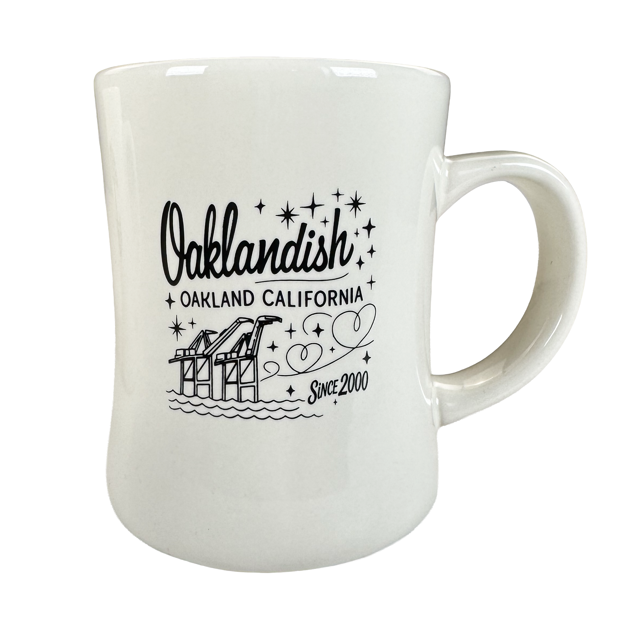 The Oaklandish Cranes Diner Mug is a 14 oz ceramic mug with "Oaklandish Oakland California Since 2000" in black text, illustrated cranes, water, and stars. Its curved design includes a comfy handle and appears against a plain white background.