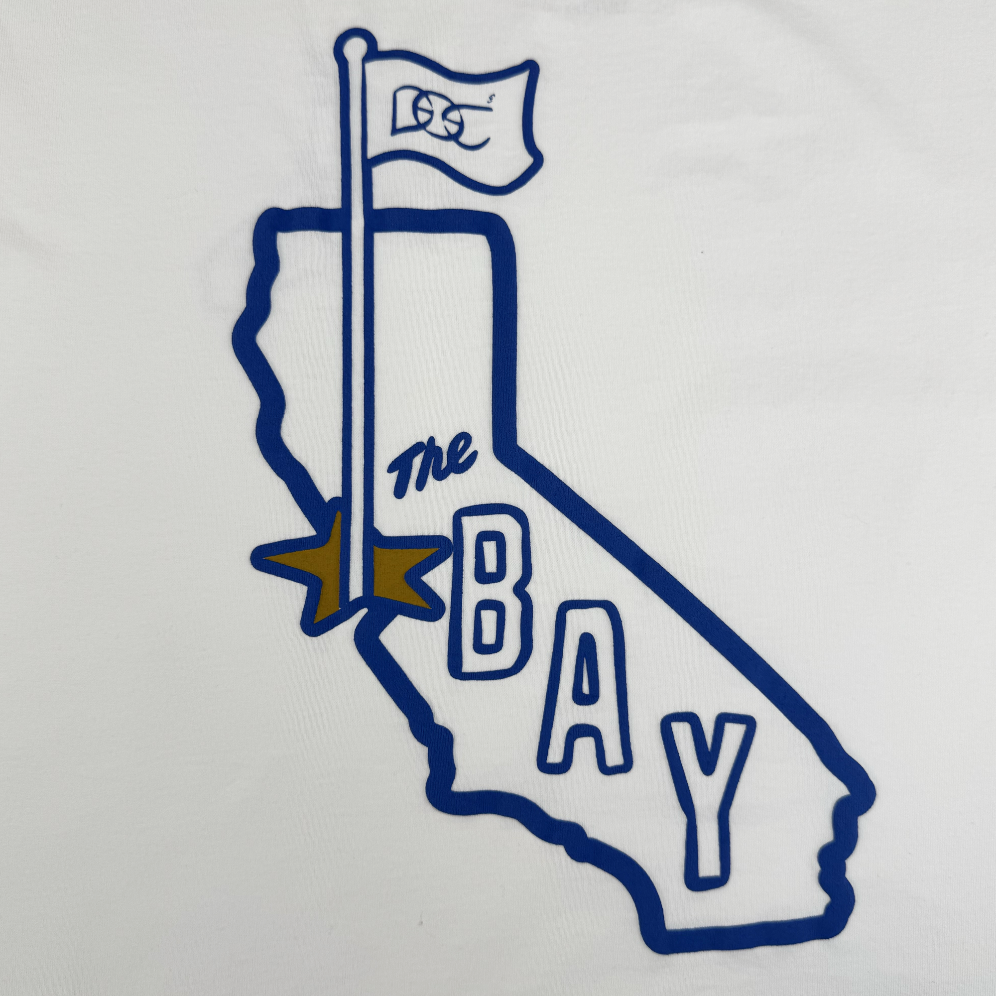The CA Bay Area Tee By DOC from Oaklandish features a blue California outline with a "GS" flag, "The BAY" text in blue and bold blue over a gold star. Part of The Bay Collection, this classic fit tee is heavyweight cotton on a white background.