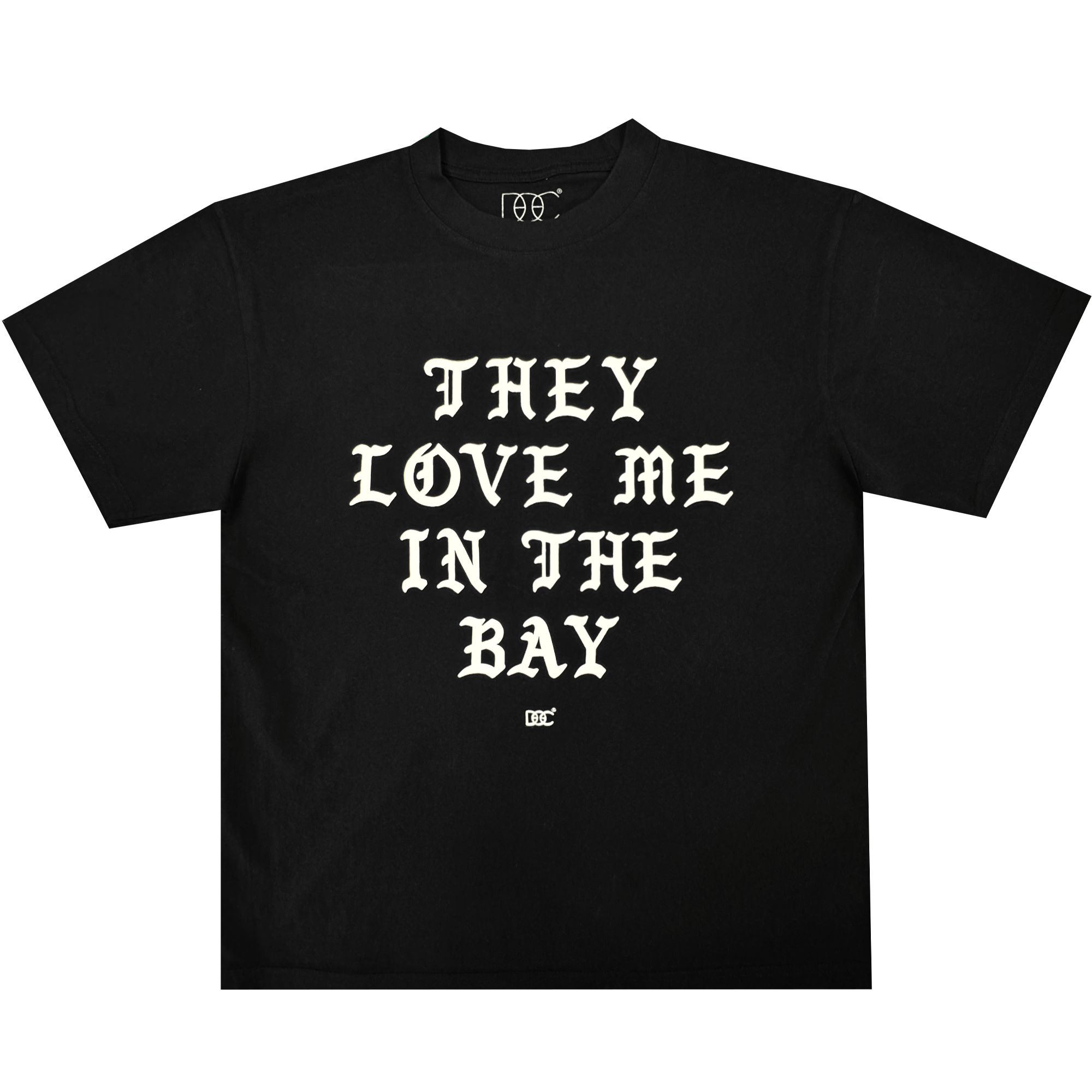 They Love Me Tee By Doc from By DOC, shown laid flat on a plain white background. This classic-fit black t-shirt is crafted from heavyweight cotton and features bold, white Old English-style lettering across the front that reads, “THEY LOVE ME IN THE BAY.” A small white By DOC logo sits just below the text at the center.