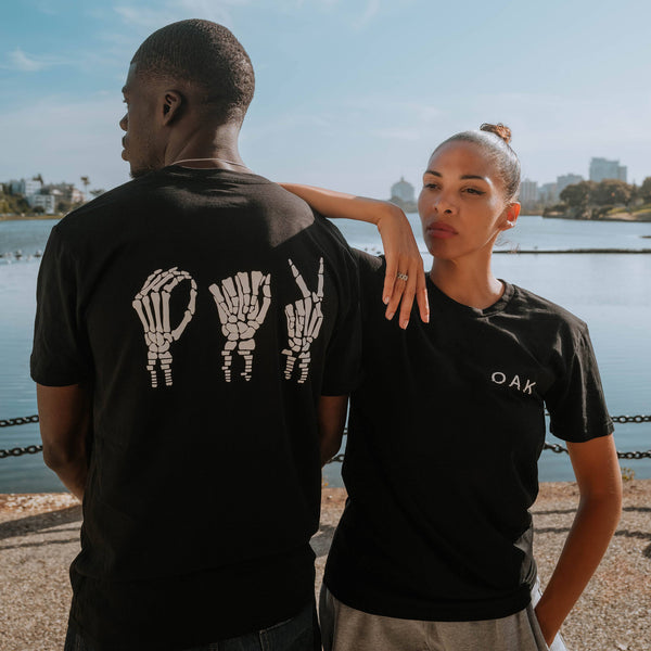 Male and female model outside wearing Oakland Gesture black t-shirts.