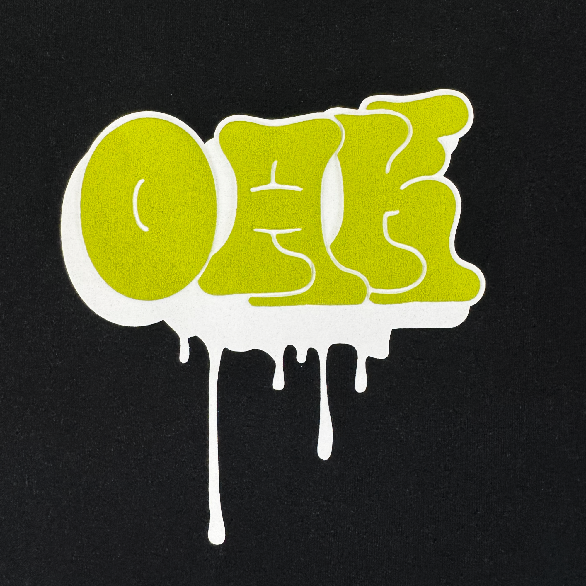 The Oaklandish Graff OAK Tee features "OAK" in bold, bright green graffiti letters with a dripping white outline on a solid black, 100% cotton classic fit.
