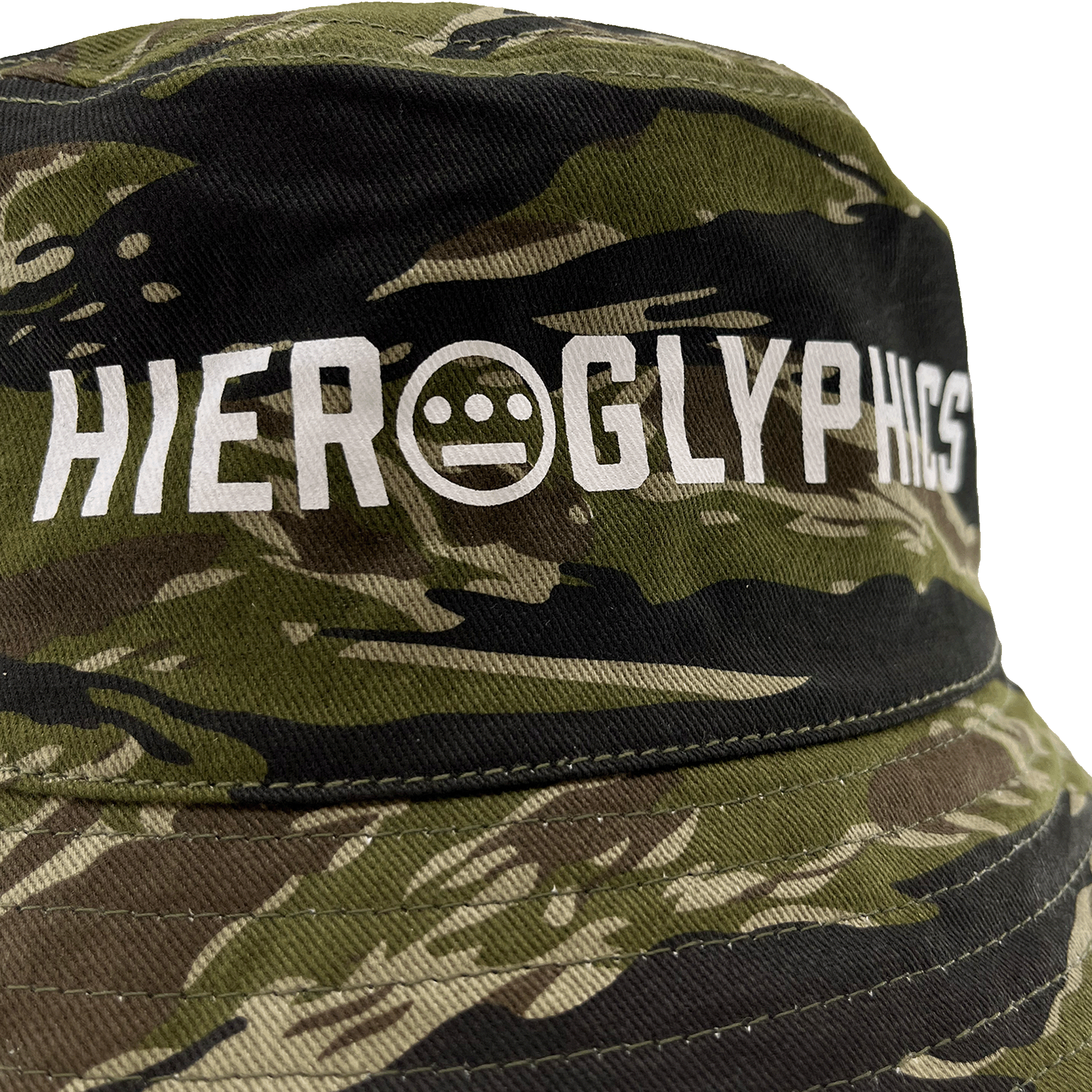 Close-up of white Hieroglyphics Hip Hop Crew wordmark with logo on the front crown of a green camouflage bucket hat. 