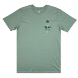 The front side of a sage green t-shirt with a small Oakland International graphic and Oaklandish tree logo on the upper chest.