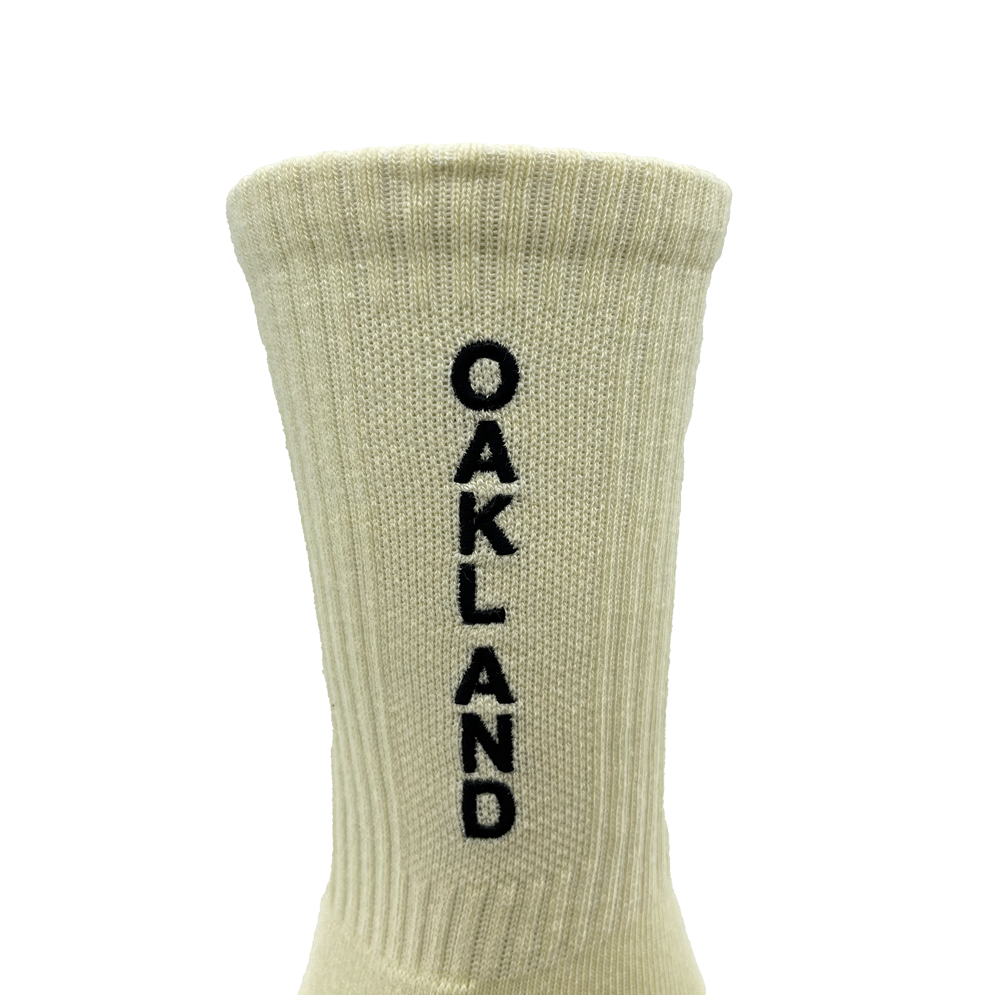 The Kanji Sock by Oaklandish is a beige ribbed cotton crew sock with "OAKLAND" stitched in black vertically down the back. Available in adult sizes, it features a cuff at the top and is set against a plain white background.