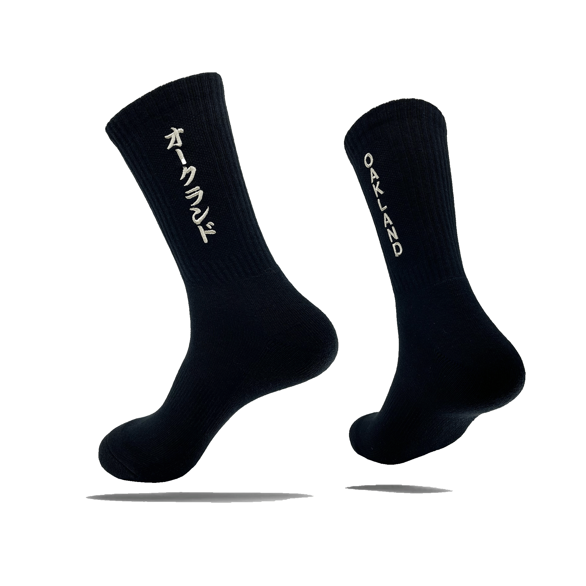 Side view of a pair of black crew socks with OAKLAND wordmark on the side of one sock and Kanji Japanese writing on the other.
