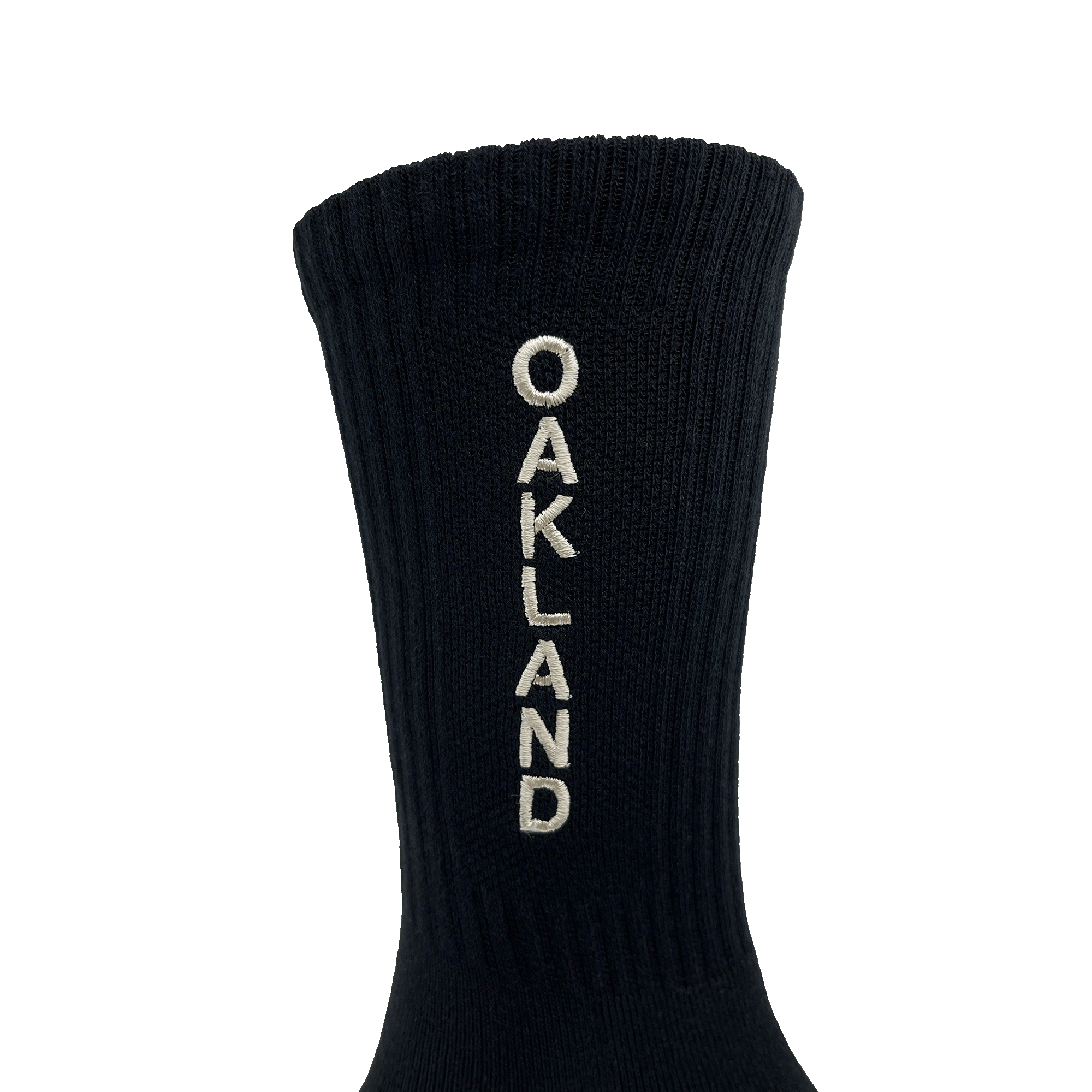 Close-up of embroidered white OAKLAND wordmark on the side of black crew sock.
