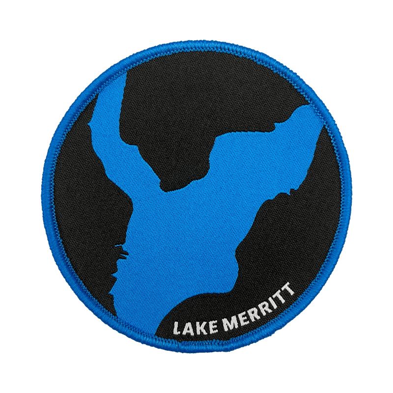 Black woven iron-on patch with blue outline of Oakland's Lake Merritt & Lake Merritt wordmark.