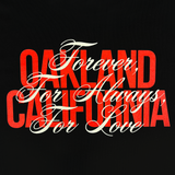 Close-up of OAKLAND CALIFORNIA wordmark in red with a white Forever. For Always. For Love in script on top on a women’s black t-shirt.