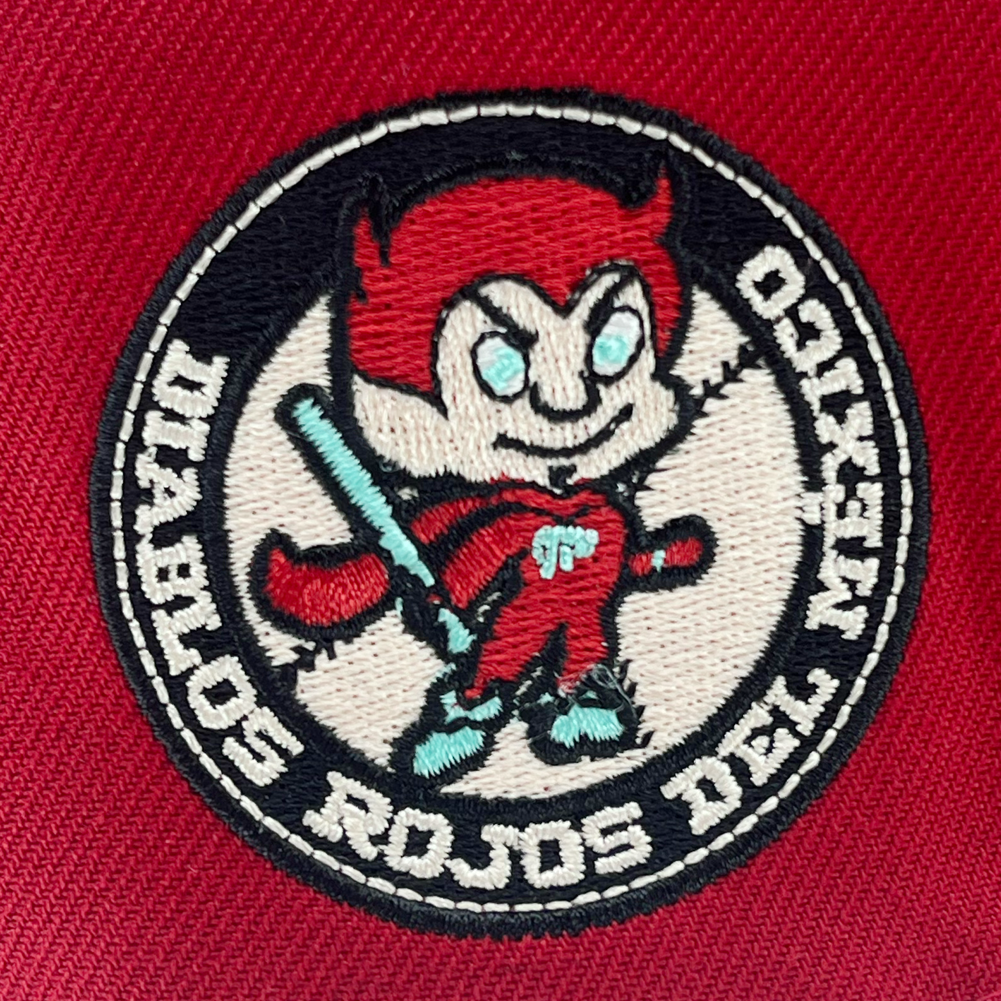 Detailed view of red diablos 59fifty fitted hat with Diablos patch on wearer's right.