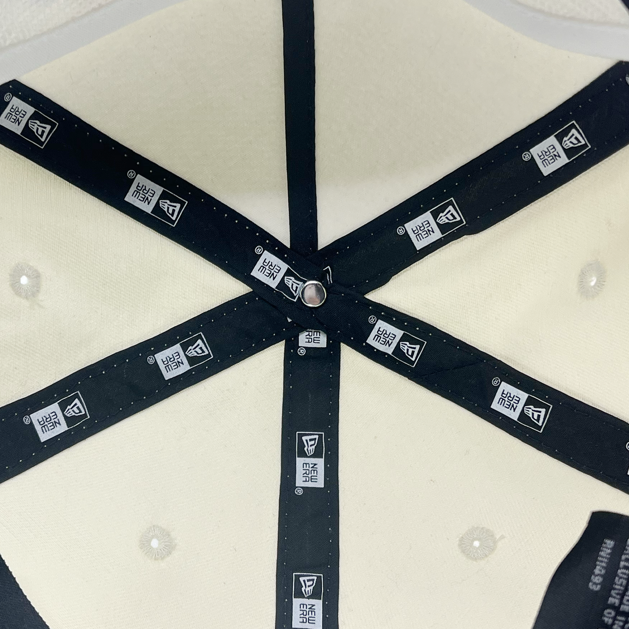 Detailed inside view of cream golfer New Era hat with New era logos on taping.
