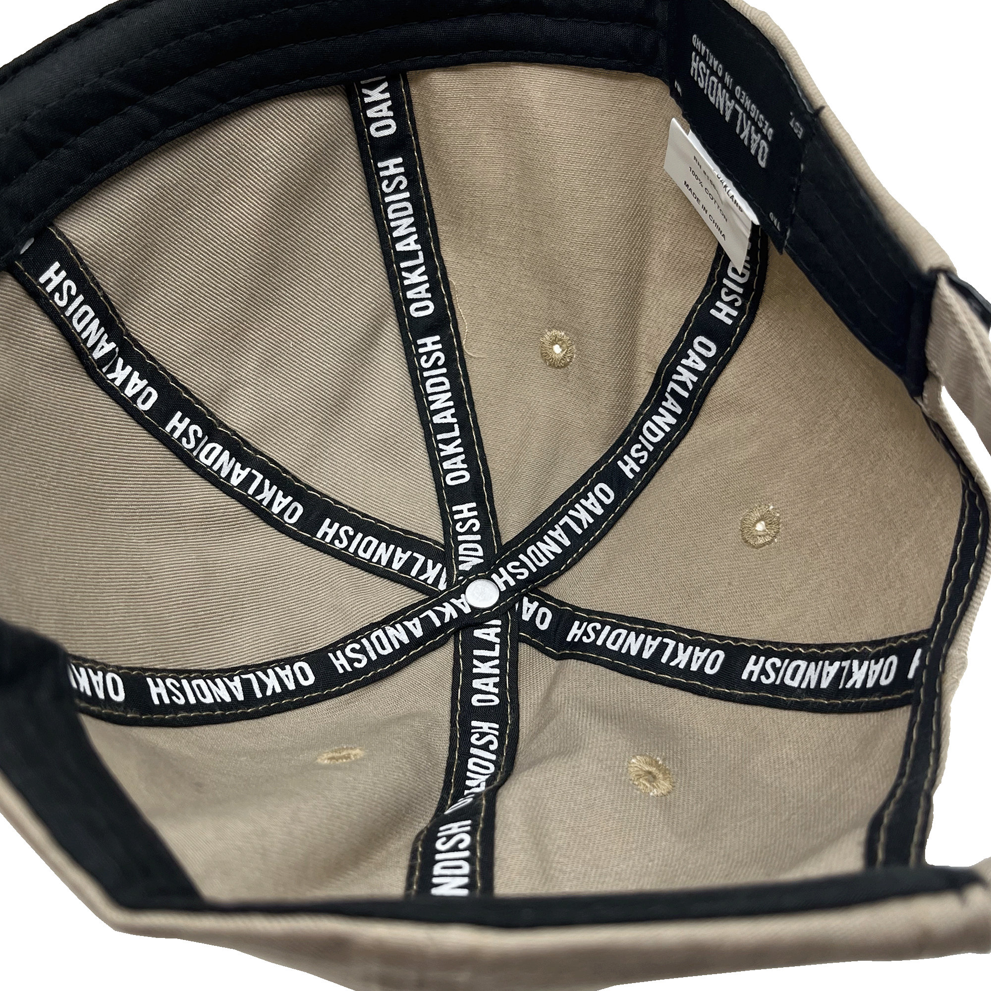 View of the black striping inside the crown of a khaki brown dad cap with a white Oaklandish wordmark on repeat.