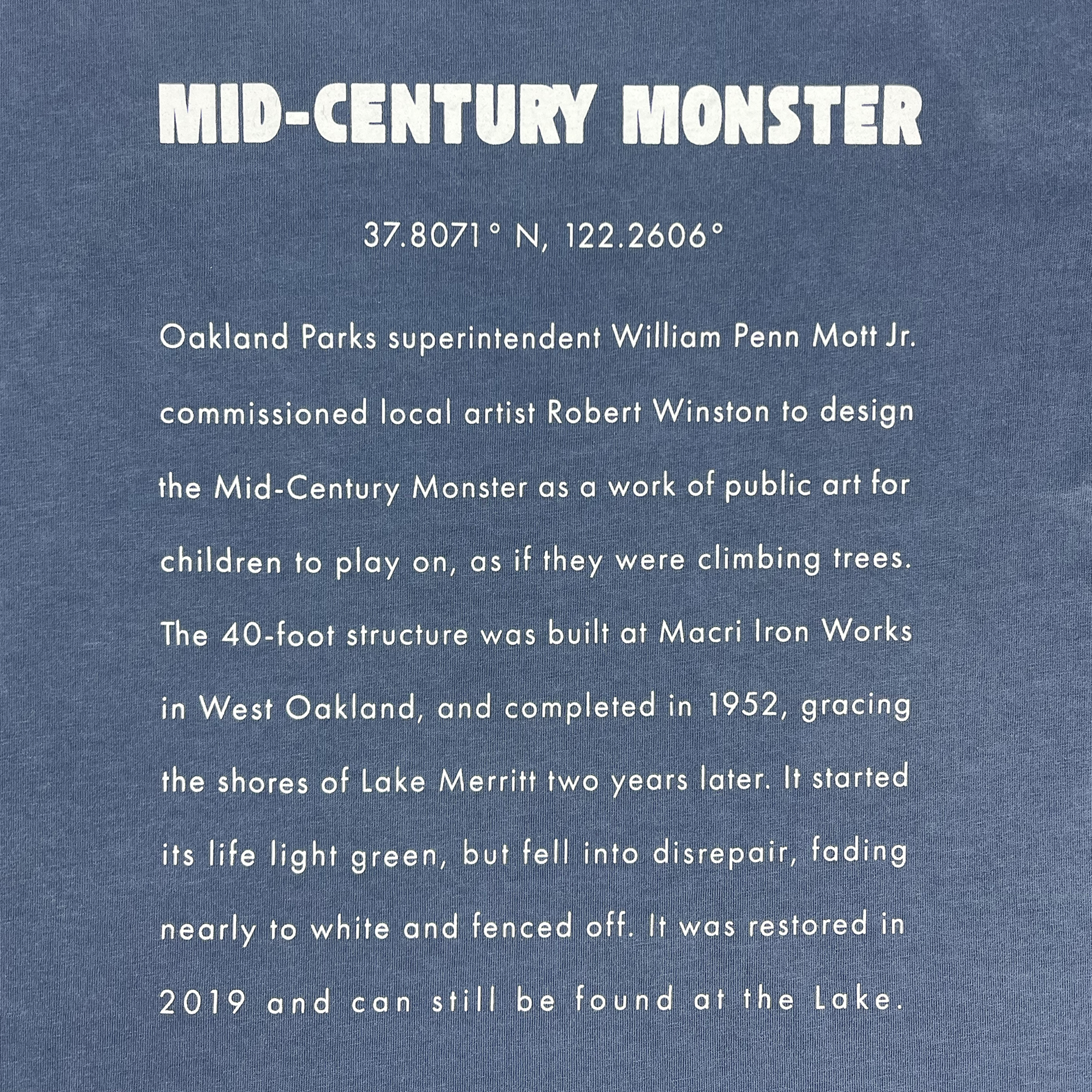 Detailed close-up long-form text explaining the history of the mid-century monster structure at Oaklands Marci Iron Works on the back of a faded blue women’s t-shirt.