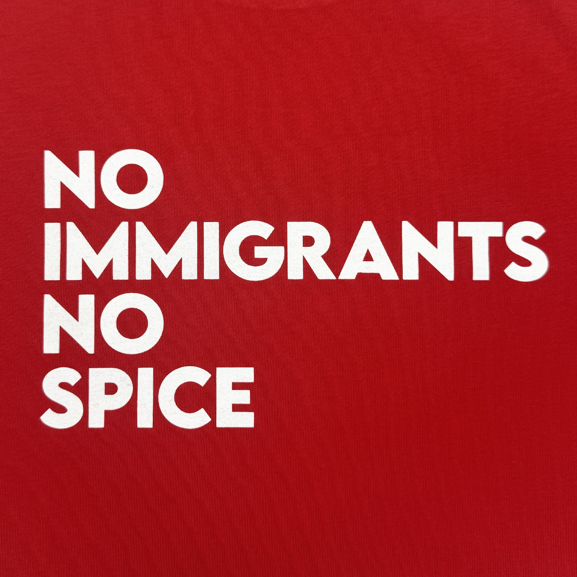 The Oaklandish NINS Crop Tee features bold white text on a red background reading “NO IMMIGRANTS NO SPICE,” combining a striking design with a #spicypride message celebrating the cultural impact of immigration.