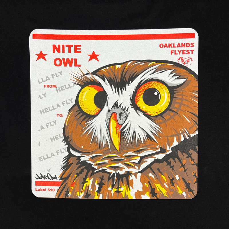 Close-up a graphic with a Burrowing Owl designed by Oakland Artist Nite Owl on a USPS sticker on a black t-shirt.