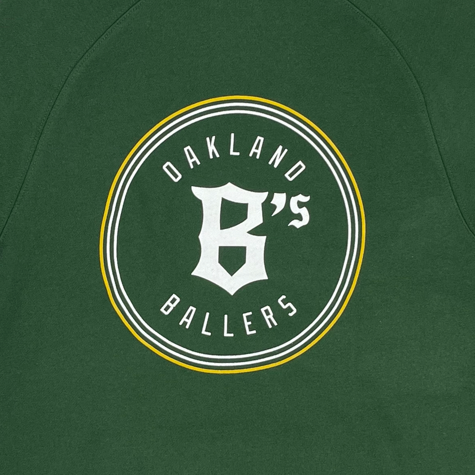 Detail photo of Oakland Ballers logo. White and Yellow circle with Oakland Ballers text on inside with B's in middle.