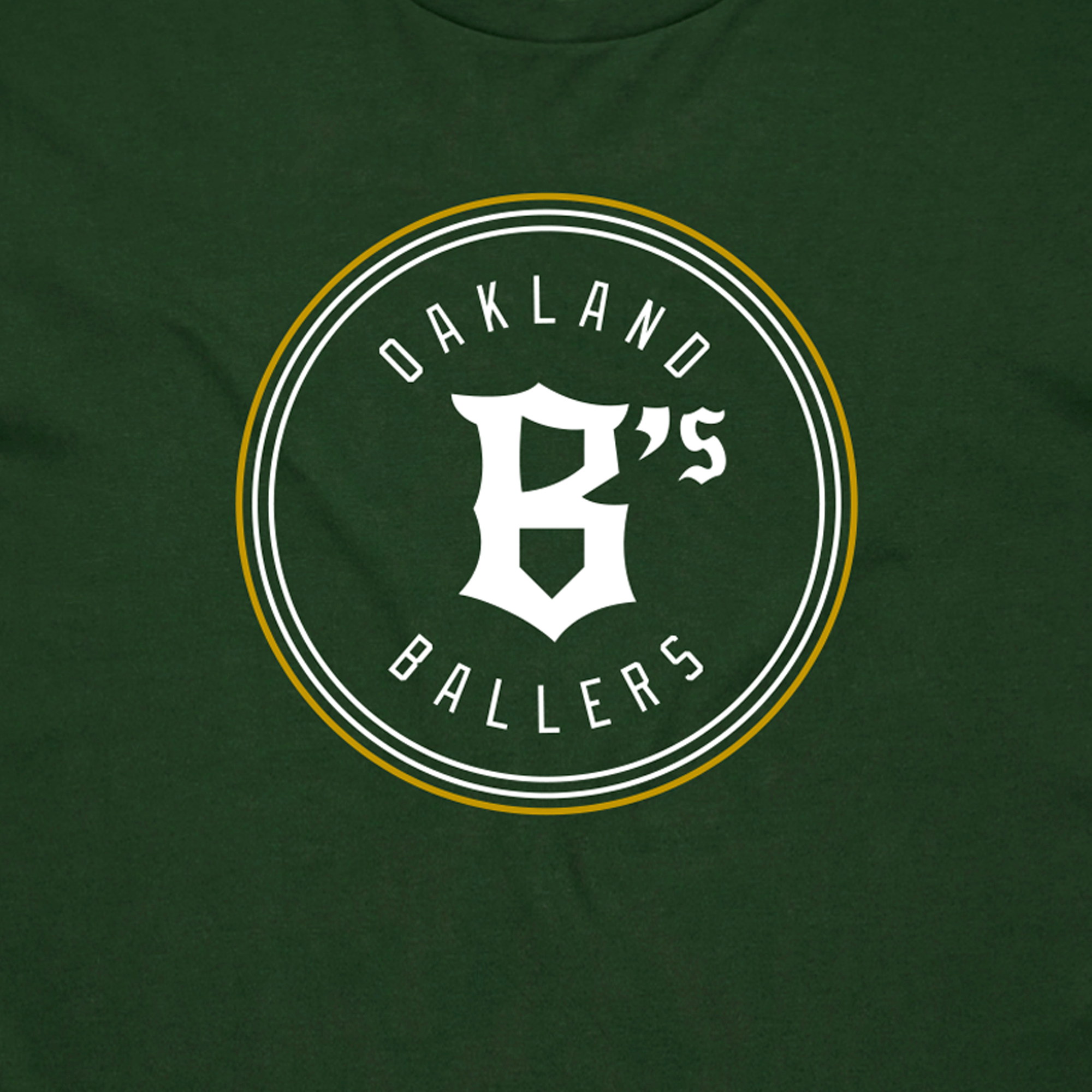 Close-up of the classic white and gold Oakland B's Ballers logo on the chest of a forest green t-shirt.