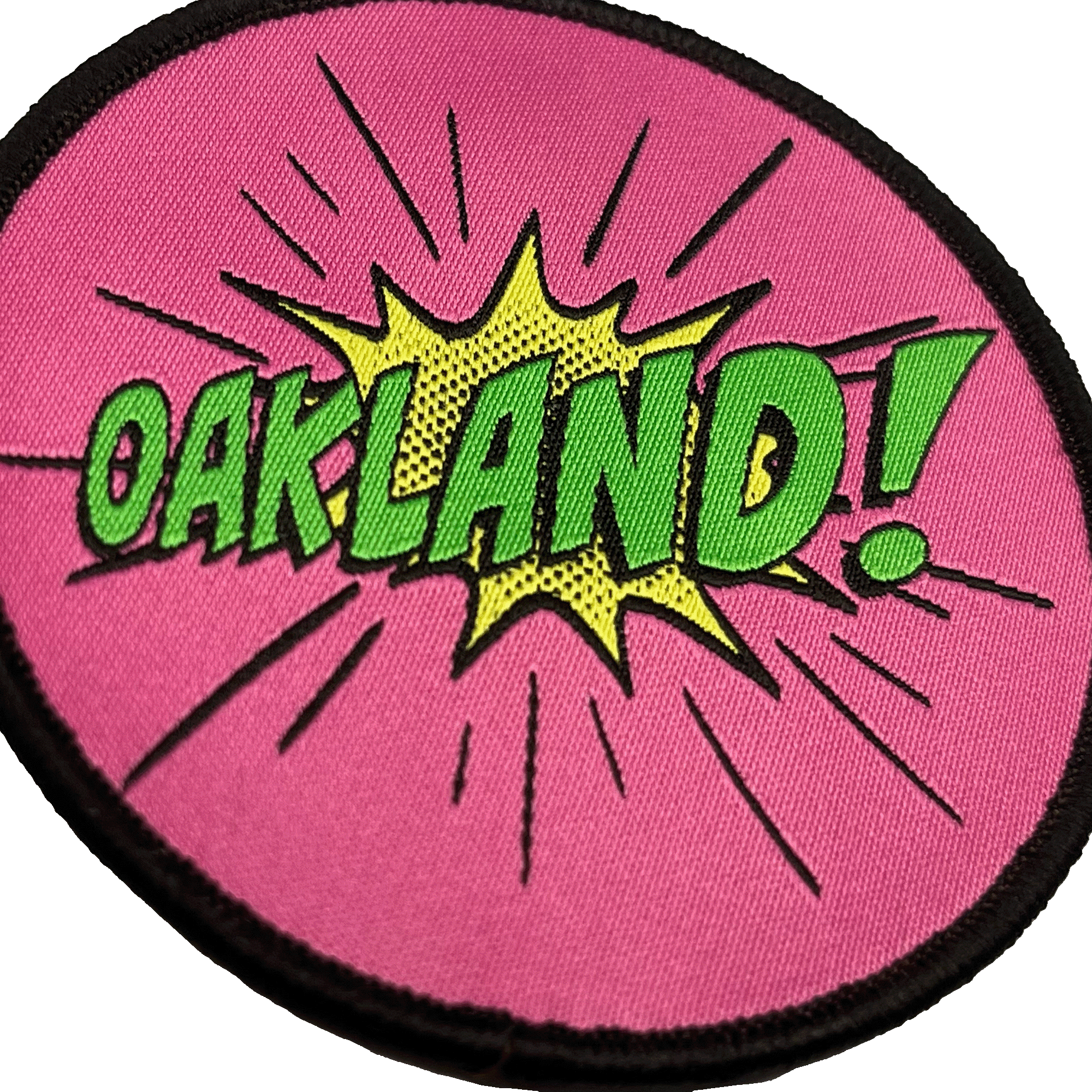 Close-up of embroidered iron-on patch with Oakland wordmark in comic cartoon punch style in pink, green and yellow.