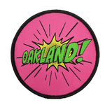 Embroidered iron-on patch with Oakland wordmark in comic cartoon punch style in pink, green and yellow.