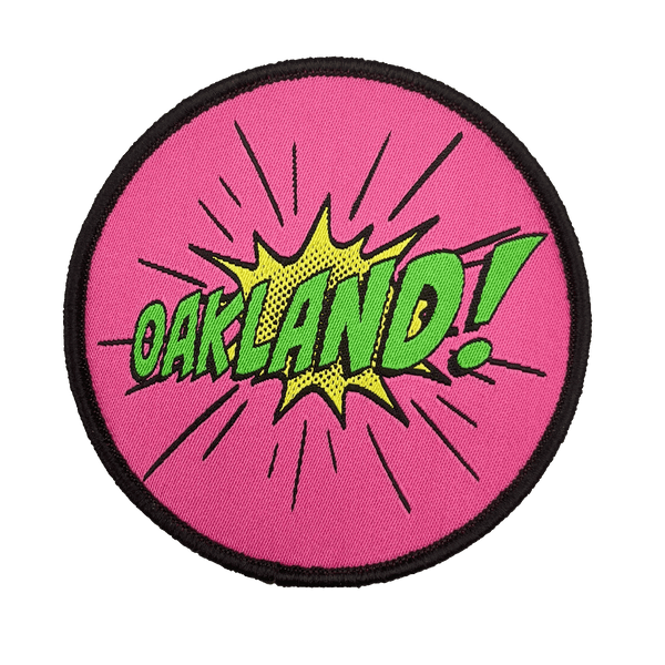 Embroidered iron-on patch with Oakland wordmark in comic cartoon punch style in pink, green and yellow.