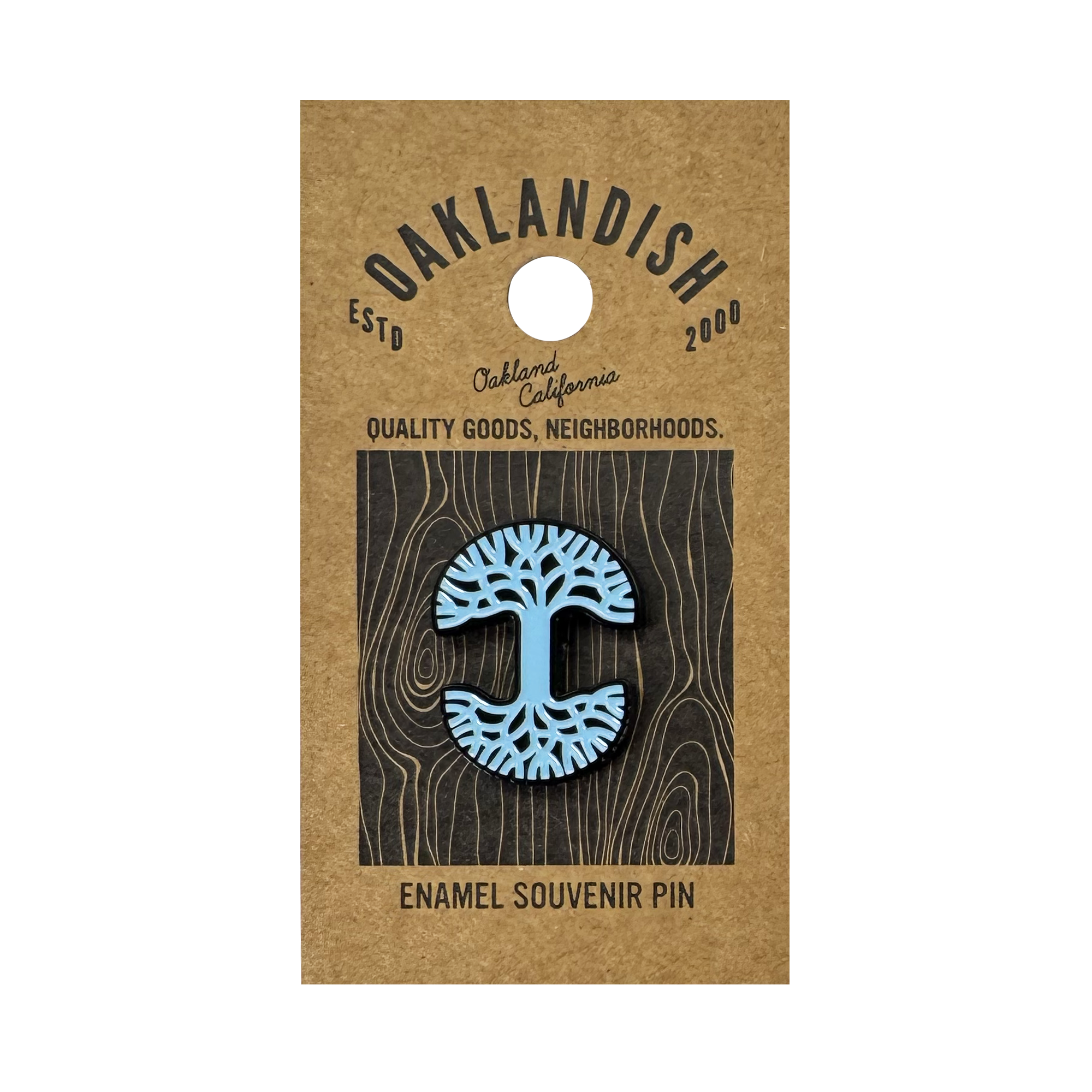 The Oaklandish Logo Enamel Pin features a blue stylized tree design and comes on a brown card reading “Oaklandish—Est’d 2000—Oakland California—Quality Goods, Neighborhoods.—Enamel Souvenir Pin.” A standout accessory.