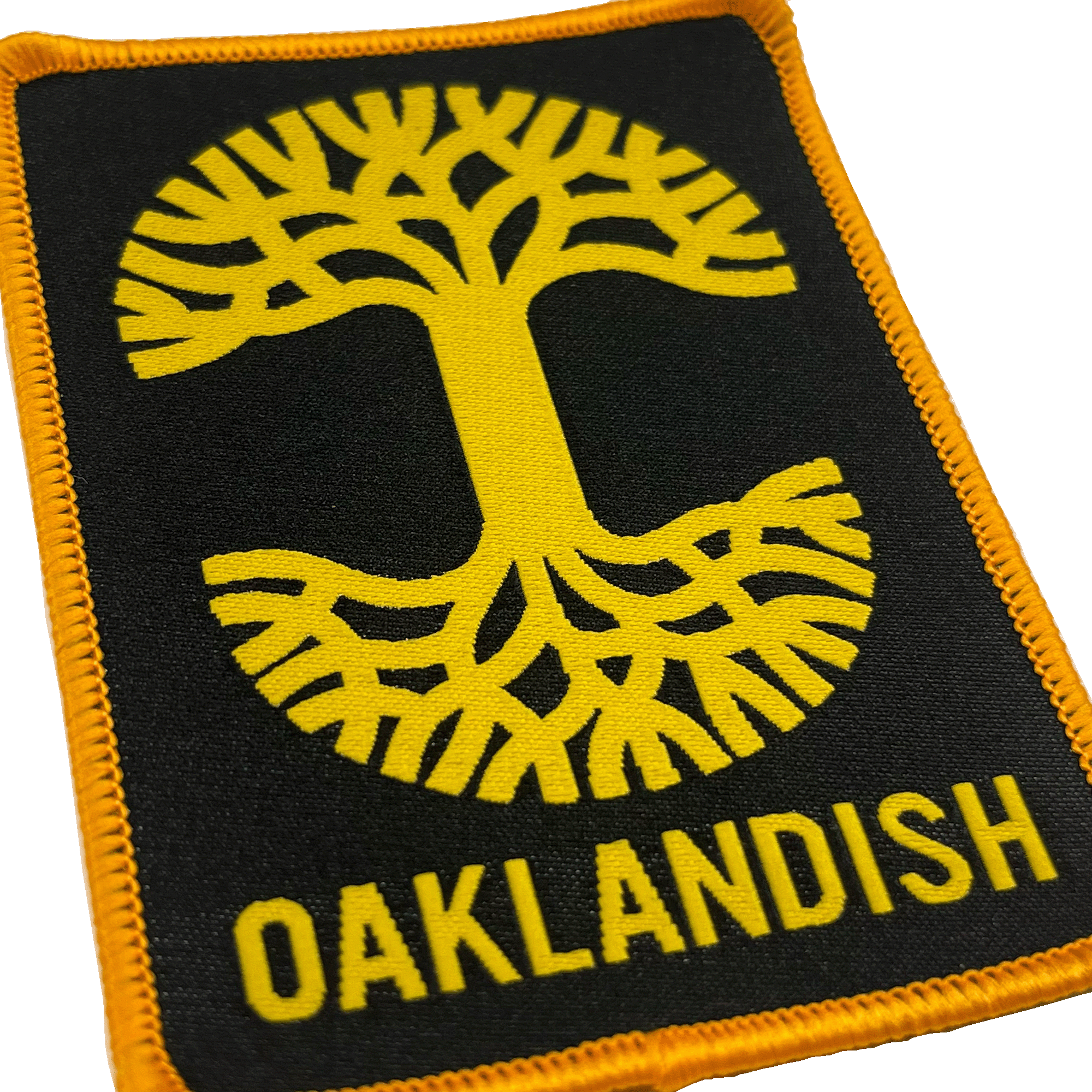 Close-up of black woven iron-on patch with gold Oaklandish tree logo and wordmark.