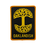 Black woven iron-on patch with gold Oaklandish tree logo and wordmark.