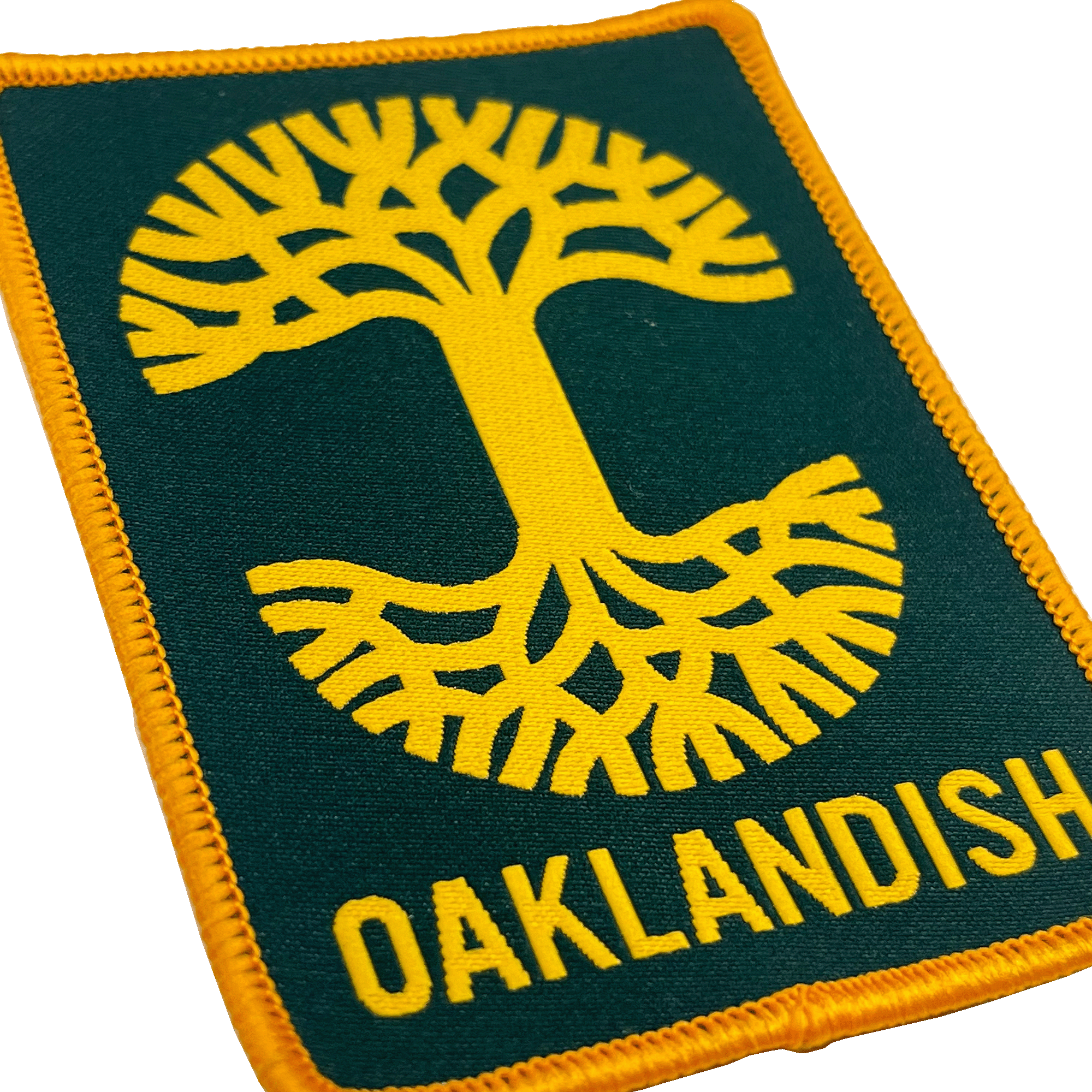 Close-up of forest green woven iron-on patch with gold Oaklandish tree logo and wordmark.