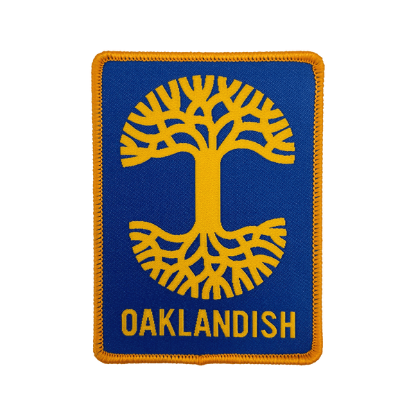 Royal blue woven iron-on patch with gold Oaklandish tree logo and wordmark.