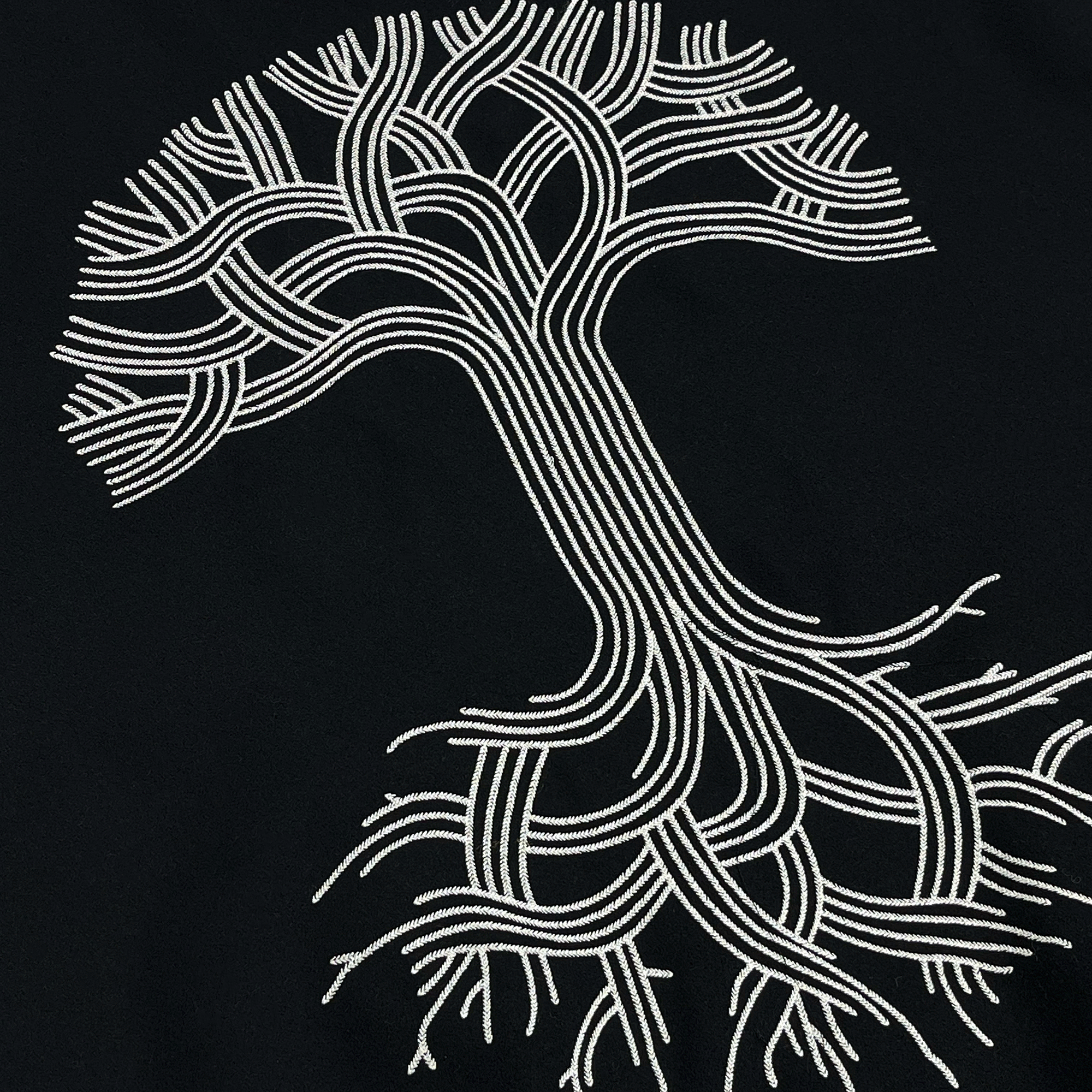  Close-up side angle view of a large Oaklandish tree logo in the center back of a black and white varsity jacket.