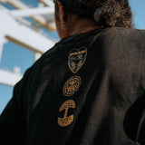 Backside view of model wearing black limited edition long-sleeve t-shirt with three logo marks - Oaklandish, Panther Power & BPLAN.